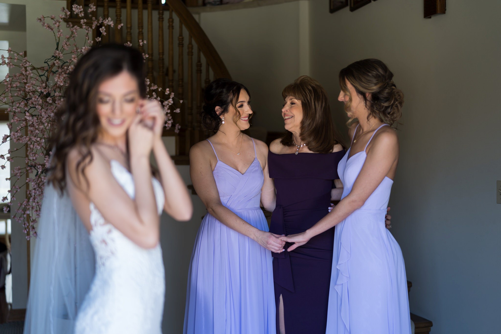 bride putting on an earring while mom and sisters look on