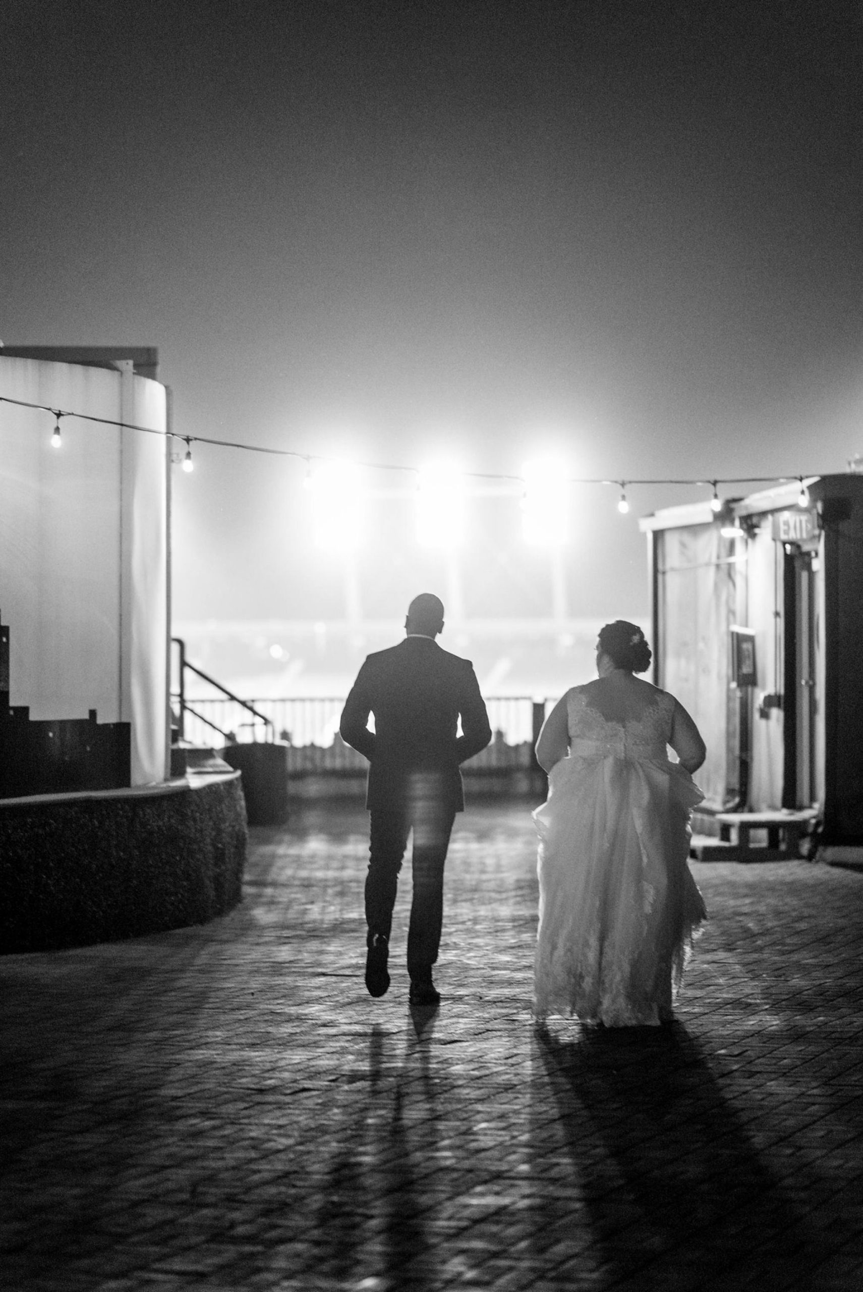 bride and groom walking away from the camera in black and white on a rooftop
