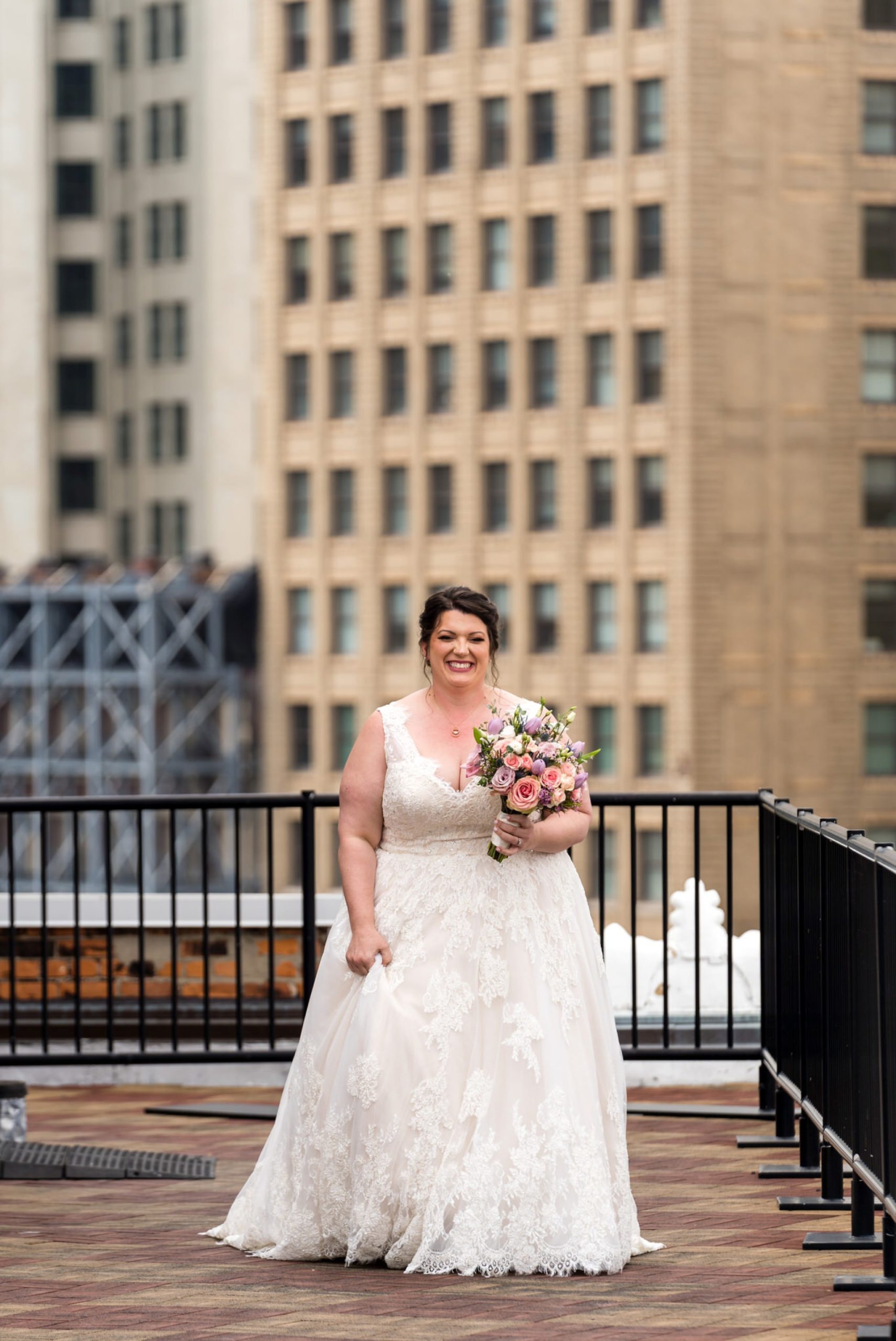 a bride walks to her first look with a tall building behind her
