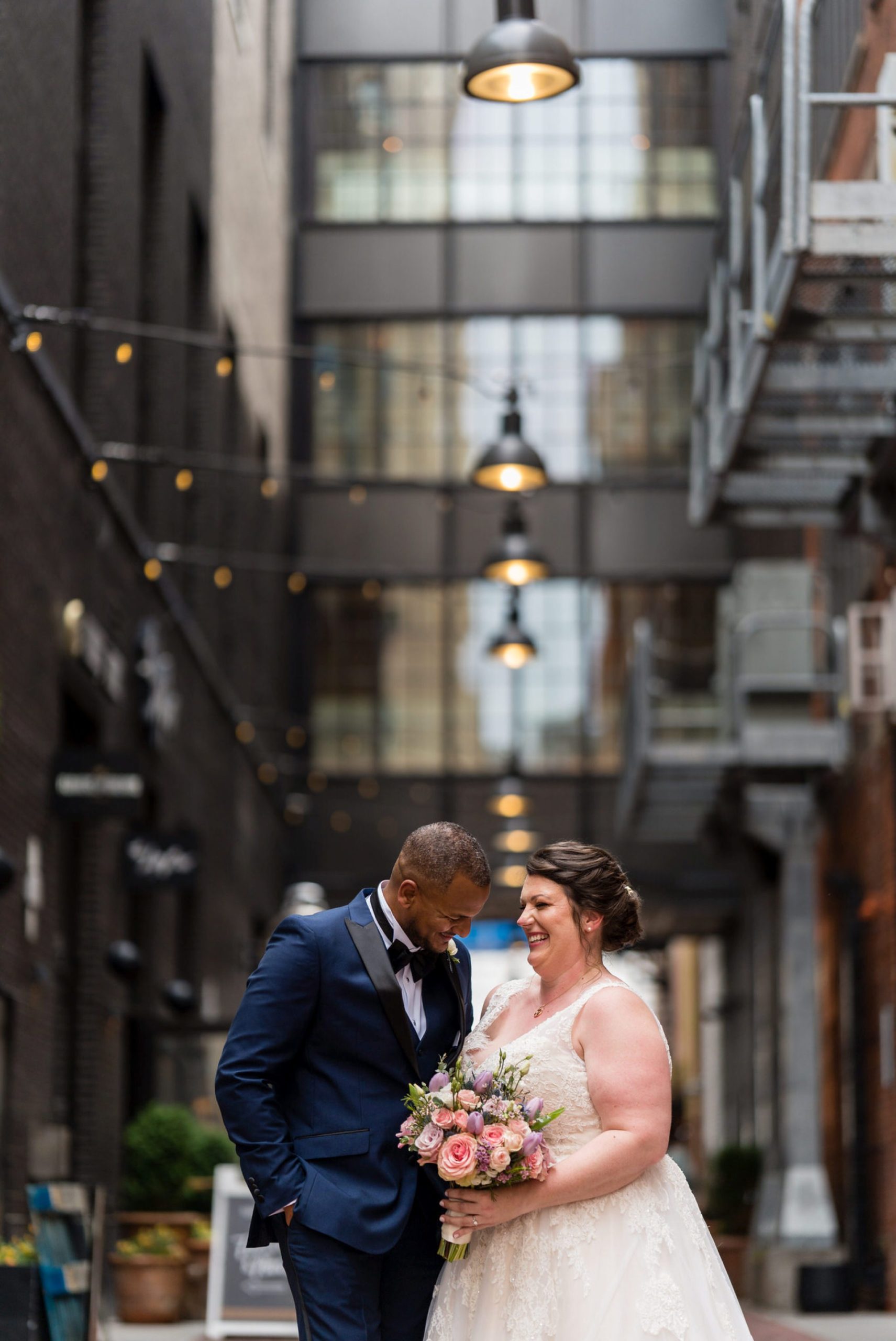 a bride and groom laugh candidly with an arm around each other in Parker's Alley Detroit