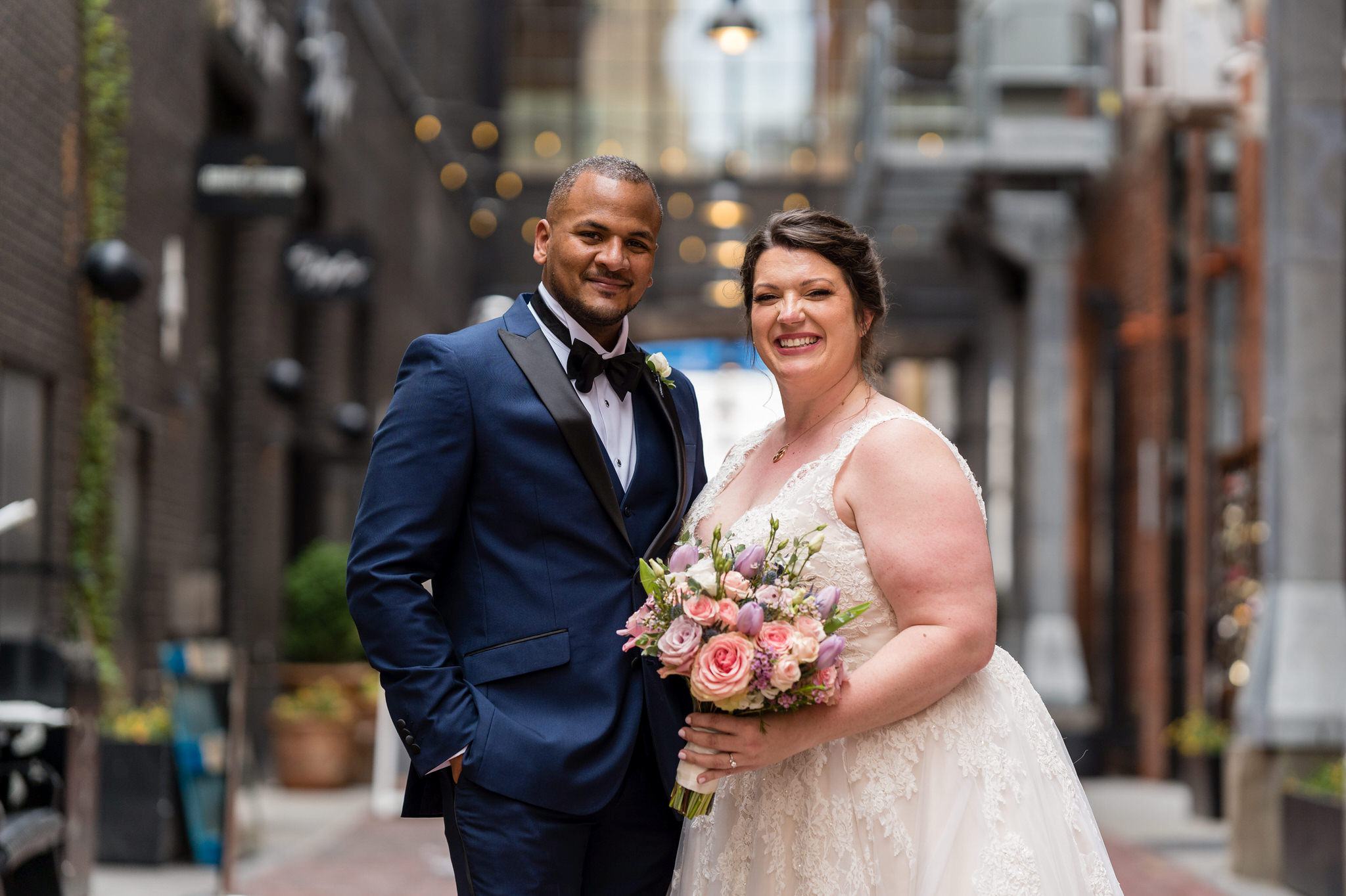 a bride and groom pose with one arm around each other in Parker's Alley Detroit