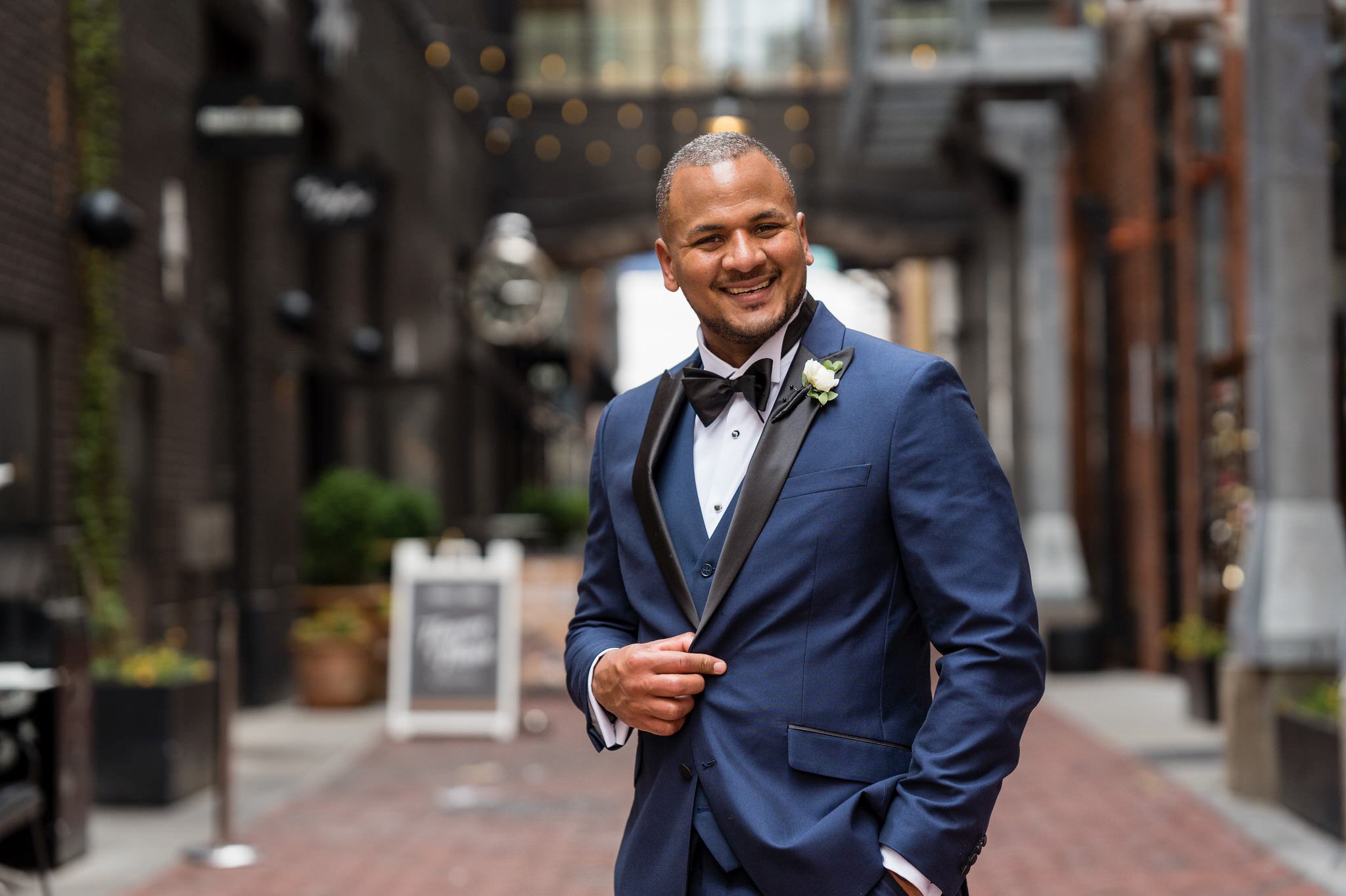 a smiling groom holds his jacket in Parker's Alley Detroit