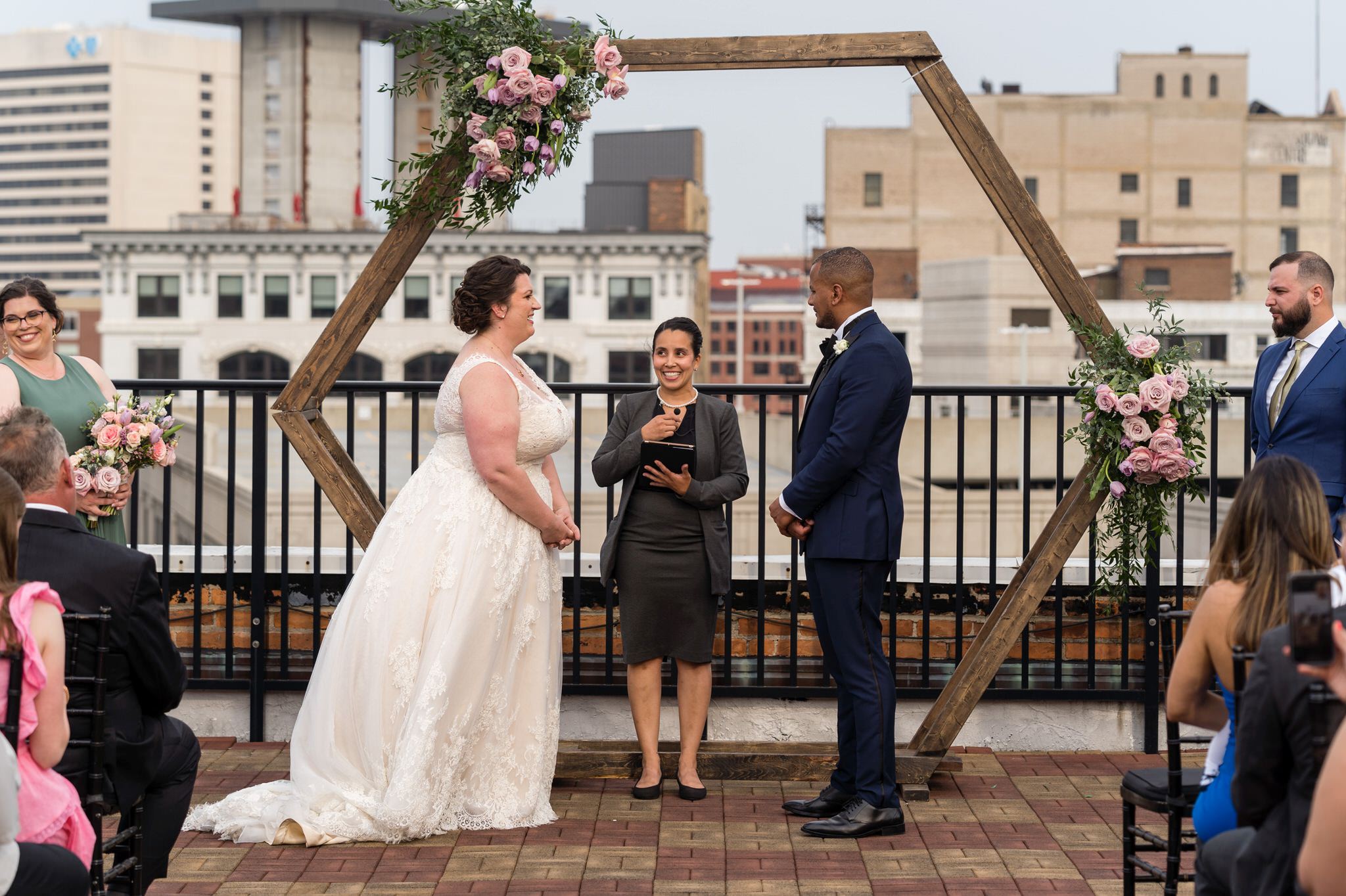 a wedding ceremony on the Detroit Opera House rooftop with the skyline behind the bride and groom 