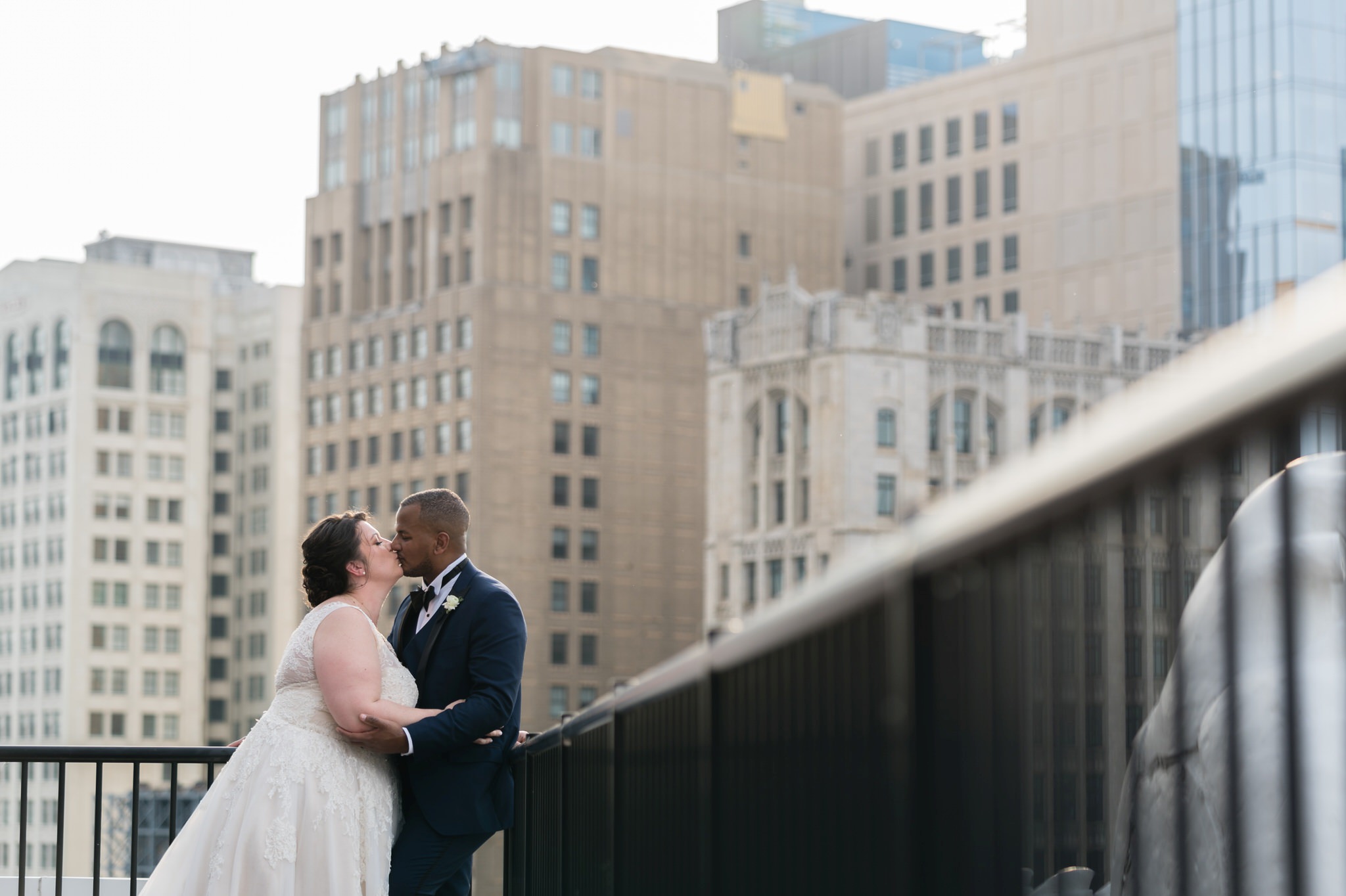 A bride and groom share a kiss with skyscrapers behind them 
