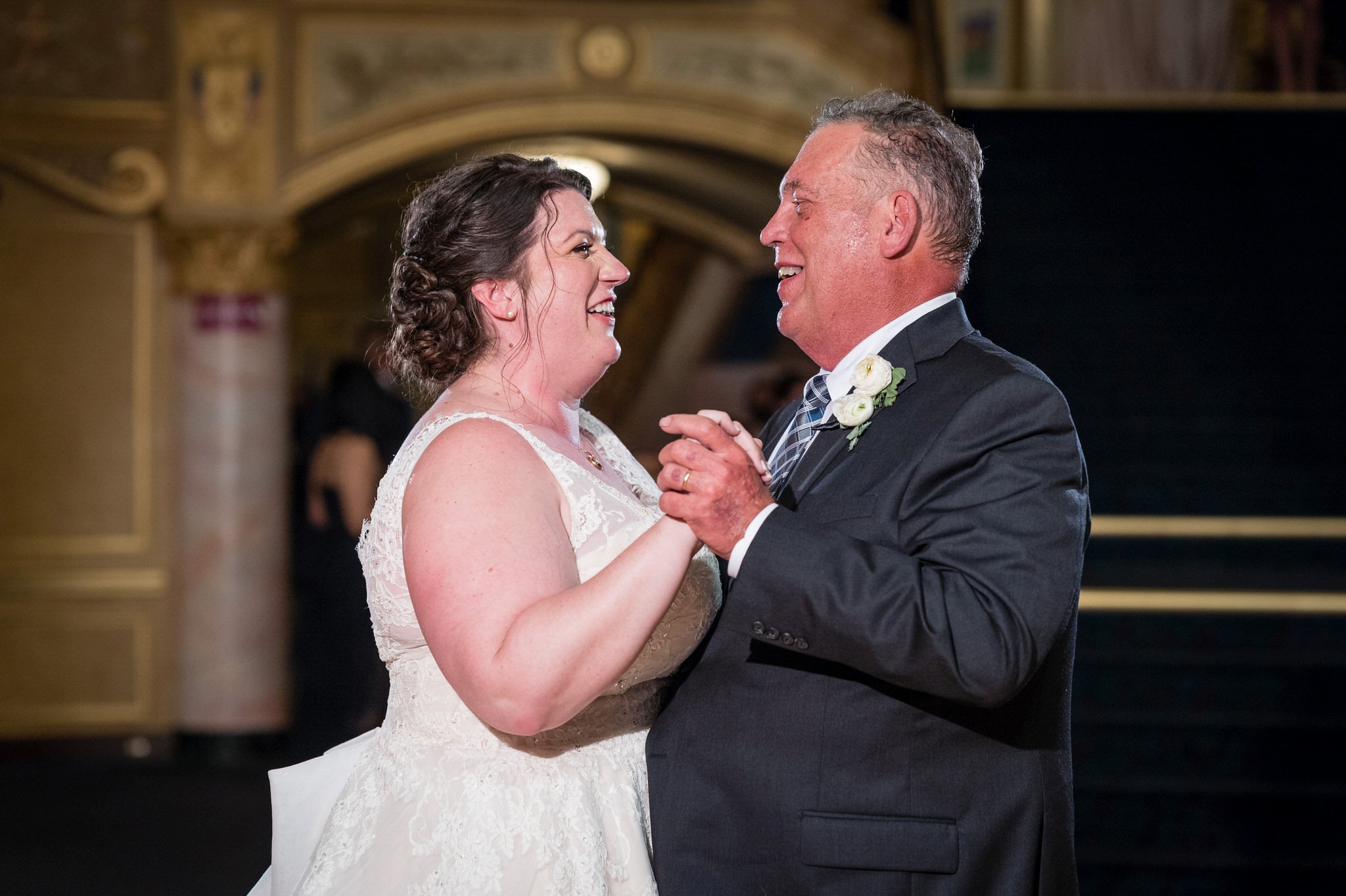 A bride and her dad dance holding hand at the Detroit Opera House