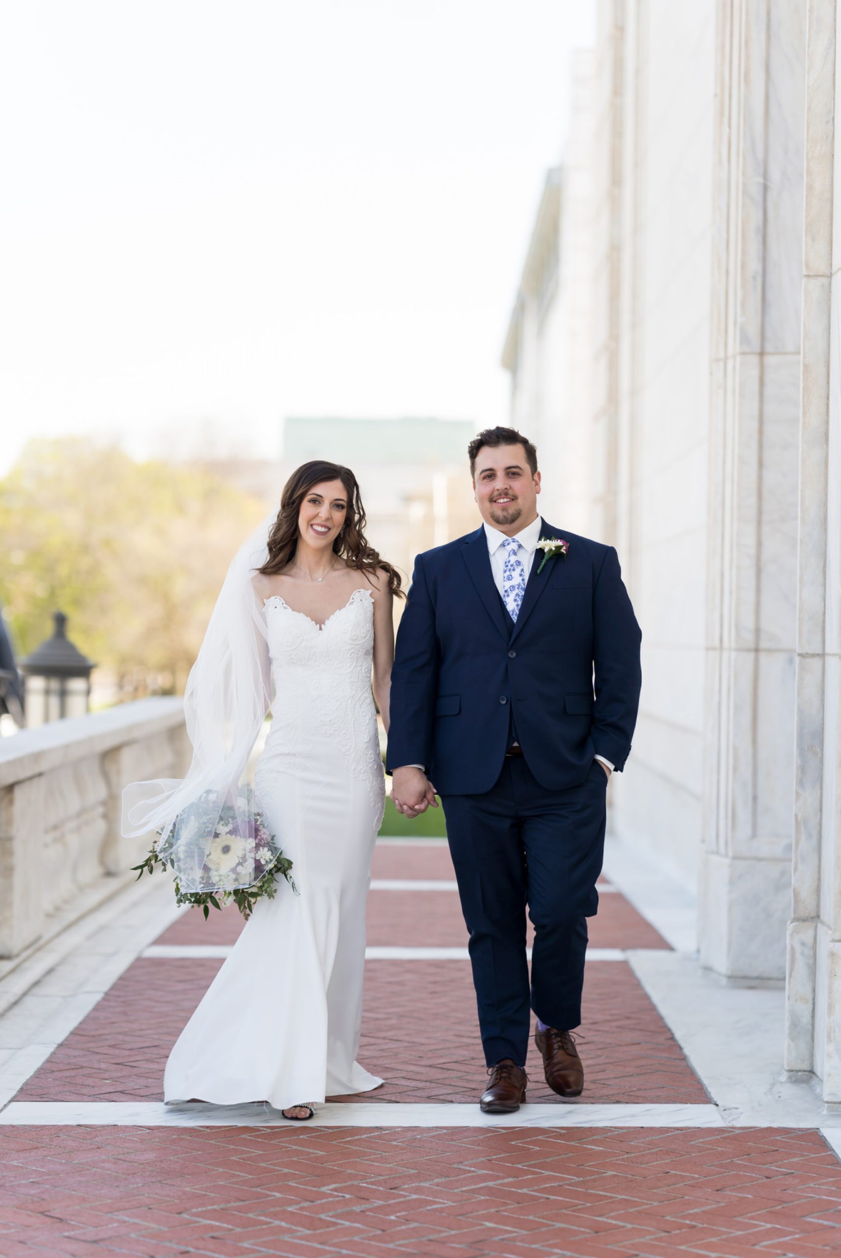 bride and groom holding hands and walking at the Detroit Institute of Arts