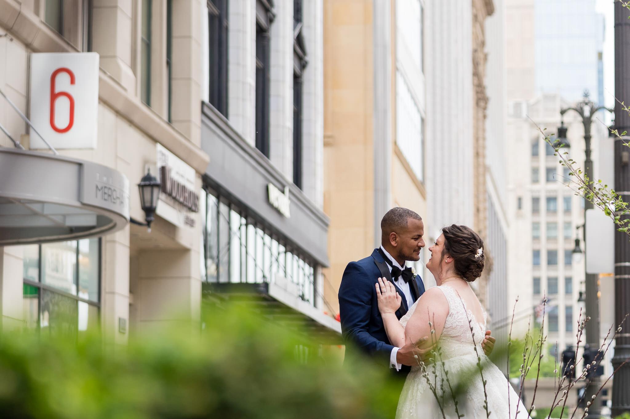 a bride and groom look at each other on a city street