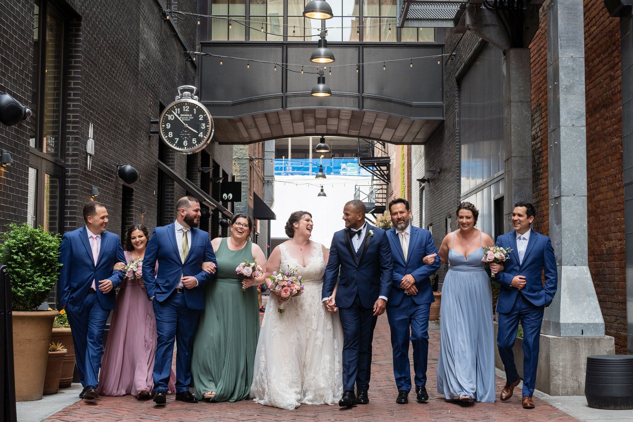 a bridal party wearing pastel colors walk in Parker's Alley Detroit