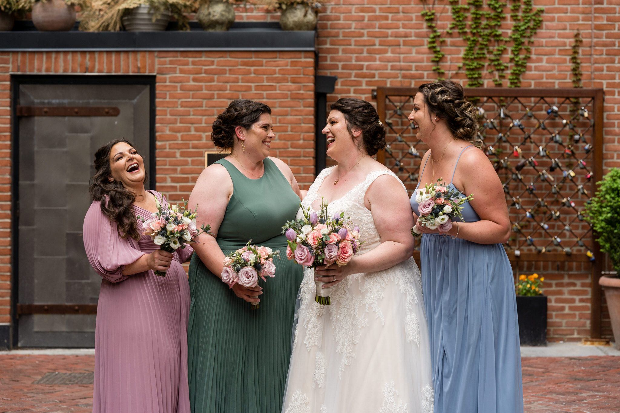 bridesmaids, wearing pastel colors, laugh in Parker's Alley Detroit