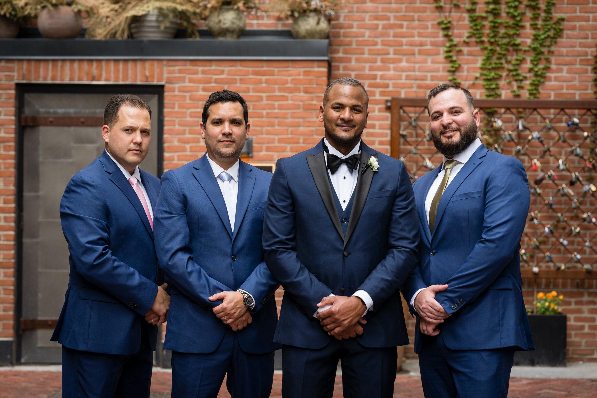 groomsmen, wearing blue tuxedos, pose in Parker's Alley Detroit