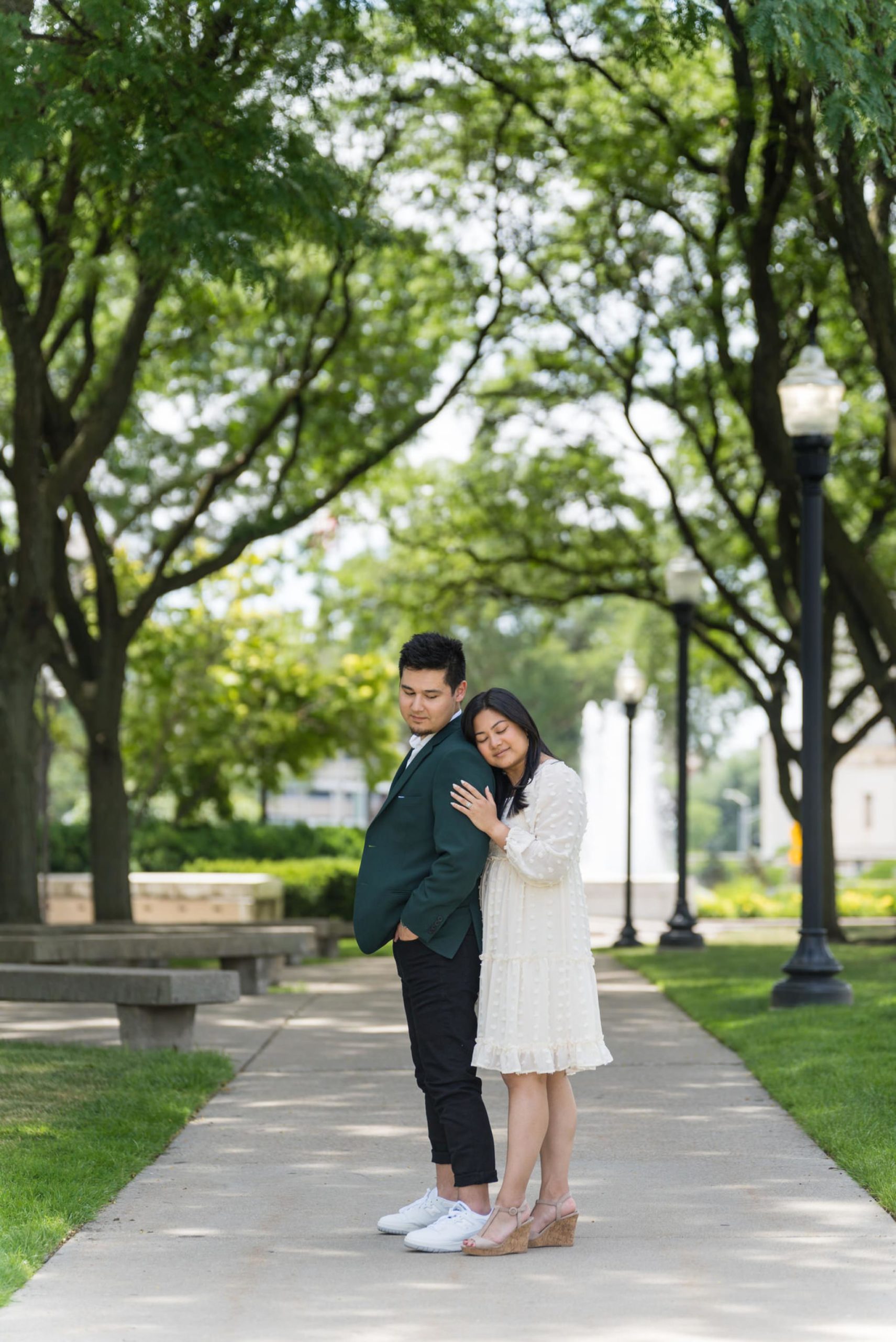 woman wearing a white sundress hugs her fiance from behind t the Detroit Institute of Arts