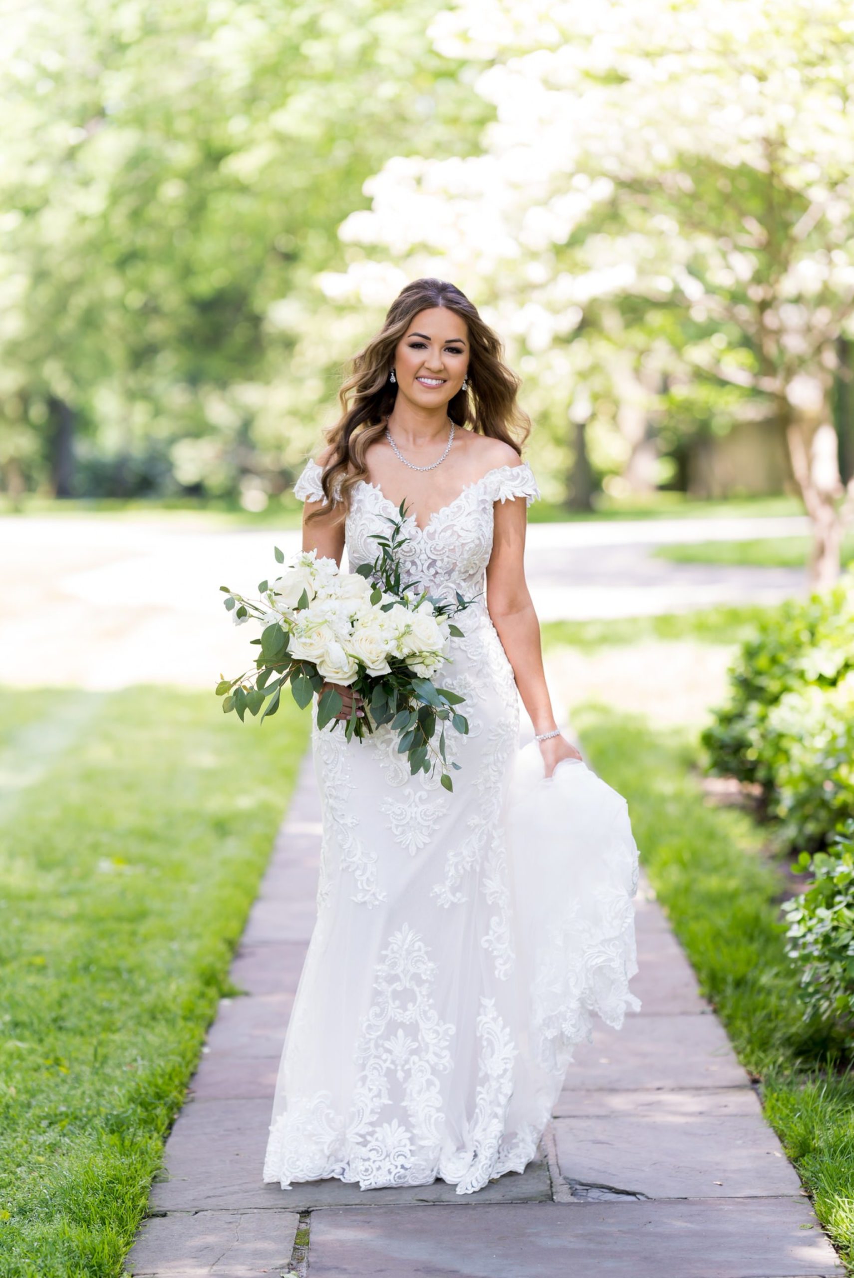 bride walks while holding her dress and white bouquet at the Edsel Ford House