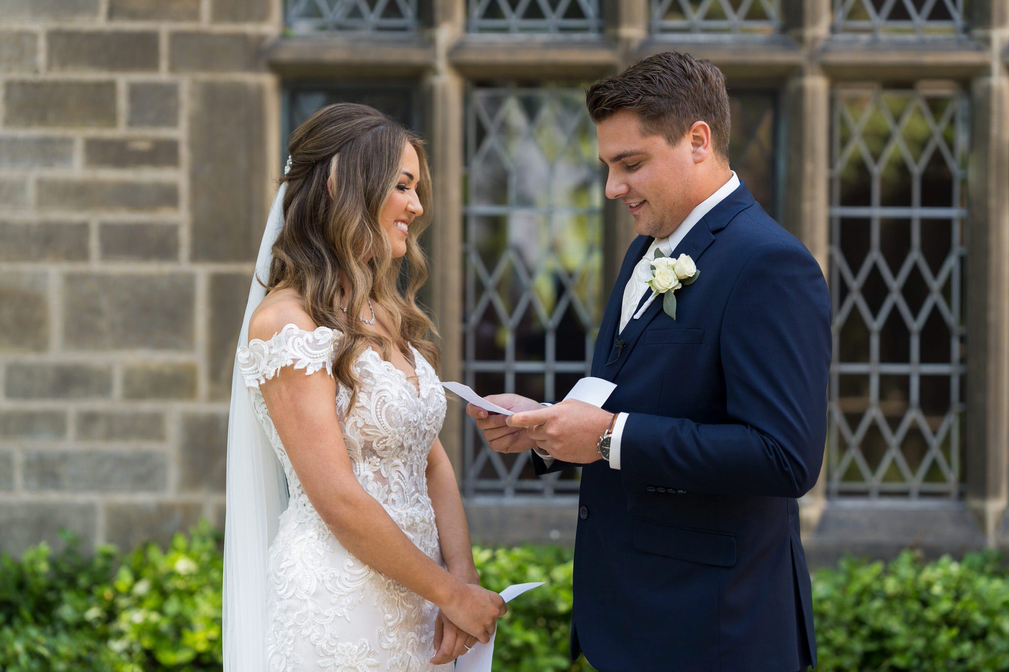 groom reads a letter while a bride smiles and looks at him