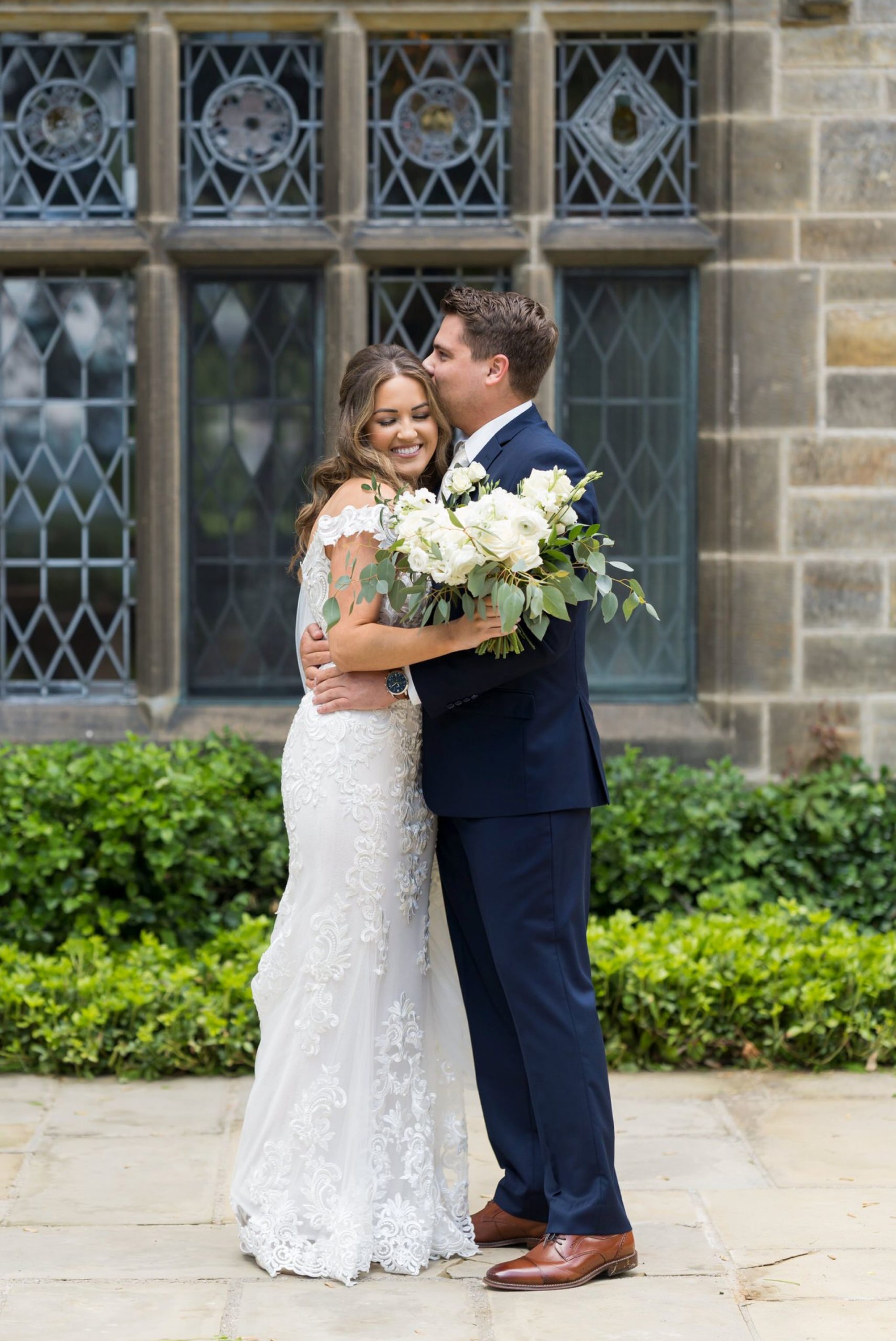 groom kisses a bride on the forehead while they hug at the Edsel Ford House