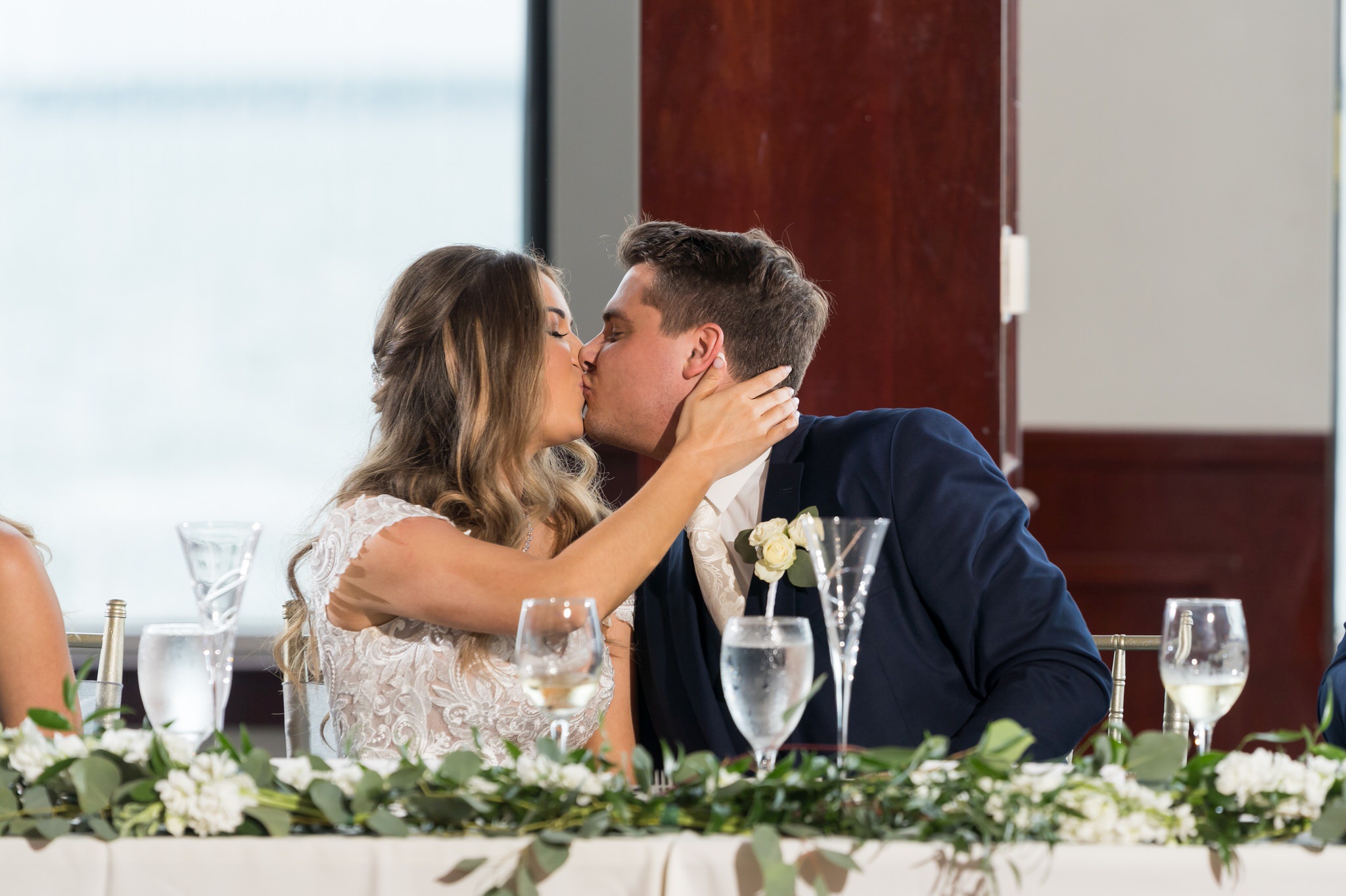 bride and groom kiss during toasts at their MacRay Harbor wedding reception