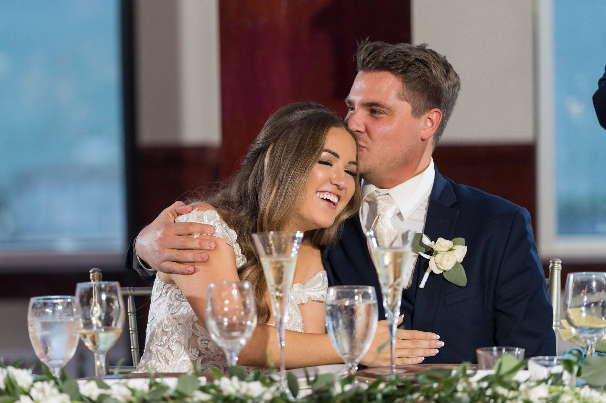 groom kisses a bride's forehead while hugging her during  MacRay Harbor wedding reception