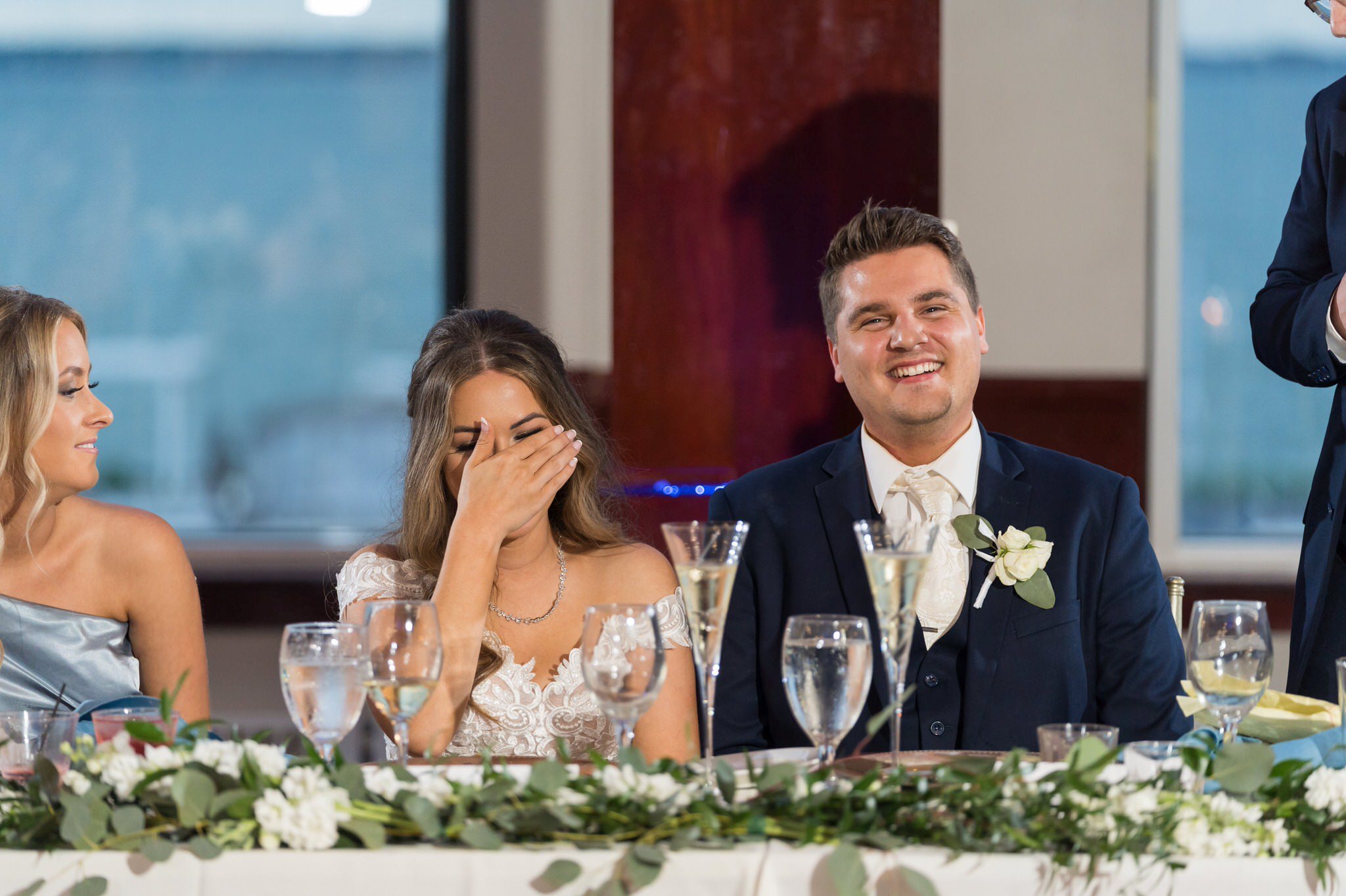 bride laughs and covers her face during speeches at a MacRay Harbor wedding reception