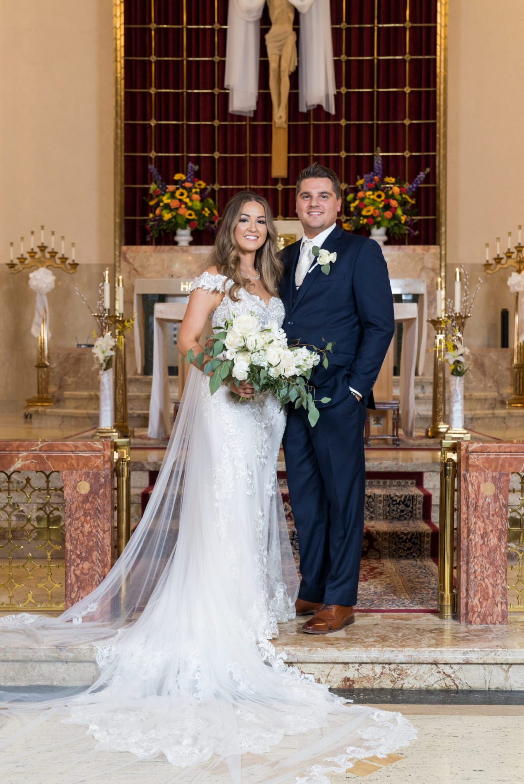 bride and groom pose at the altar of St. Peter and Paul catholic church in Mt Clemens, MI