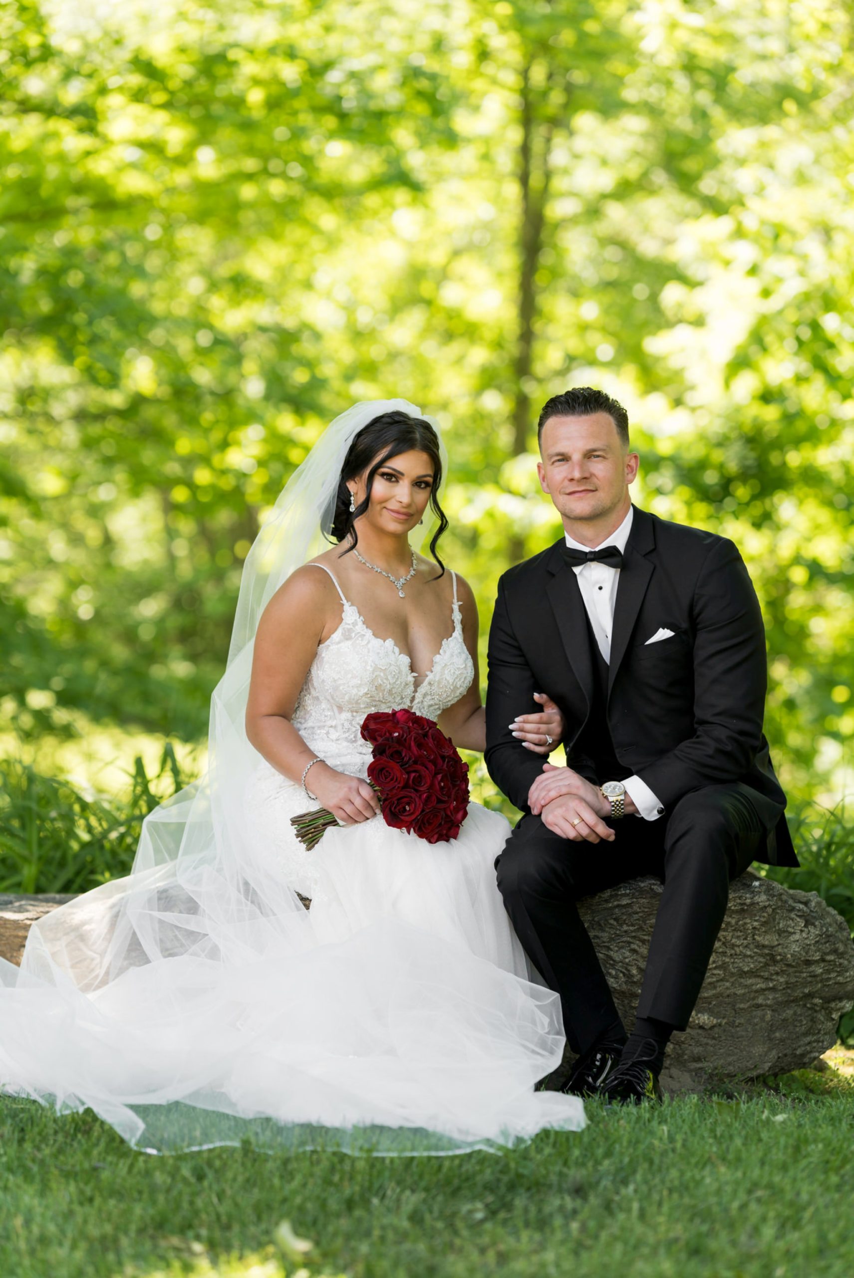 a bride and groom sit on a rock at Van Hoosen Museum wedding 