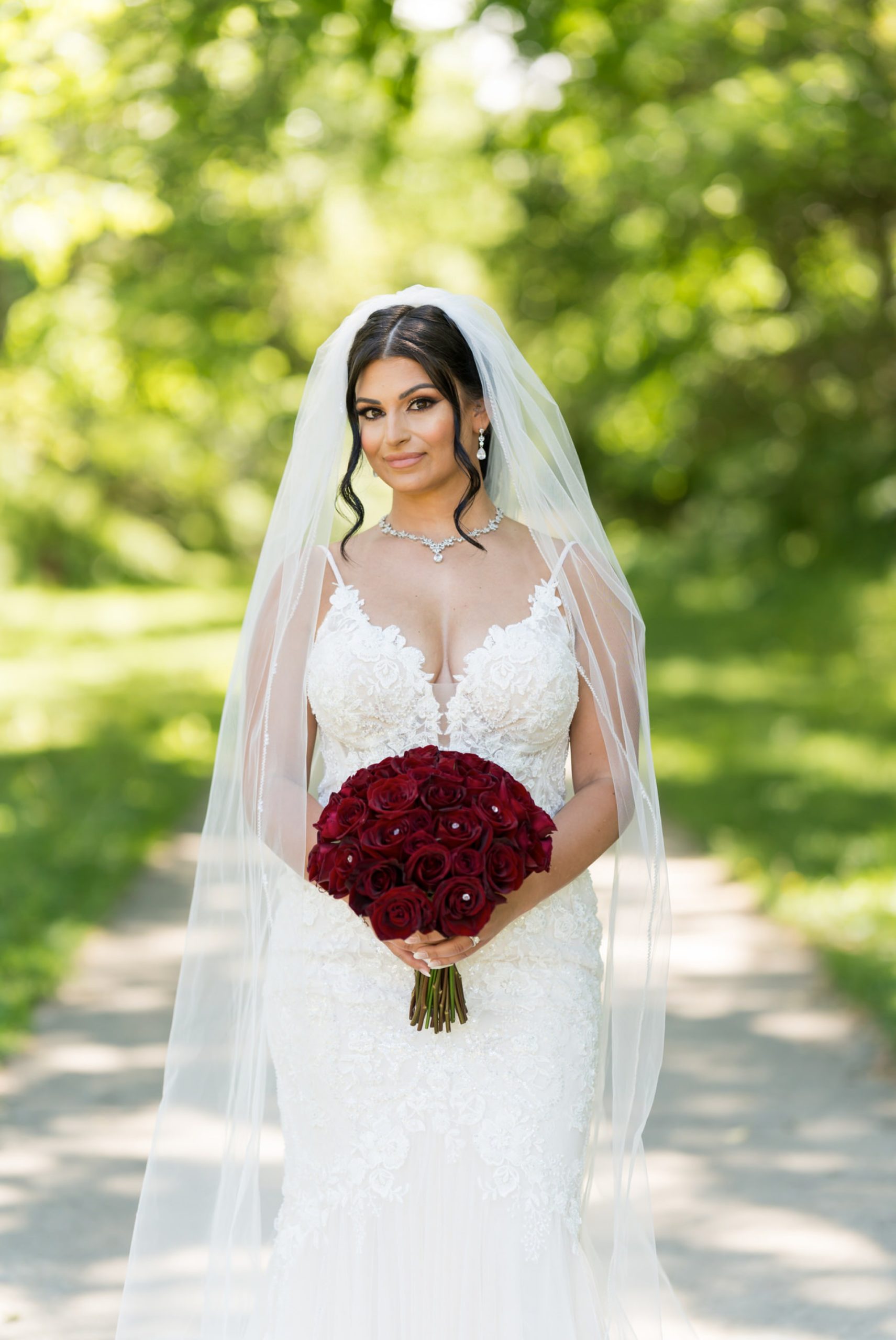 a bride holds her bouquet in a walking path at Van Hoosen