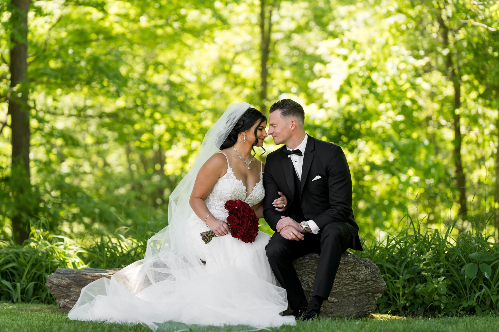 a bride and groom sit on a rock at Van Hoosen Museum wedding 