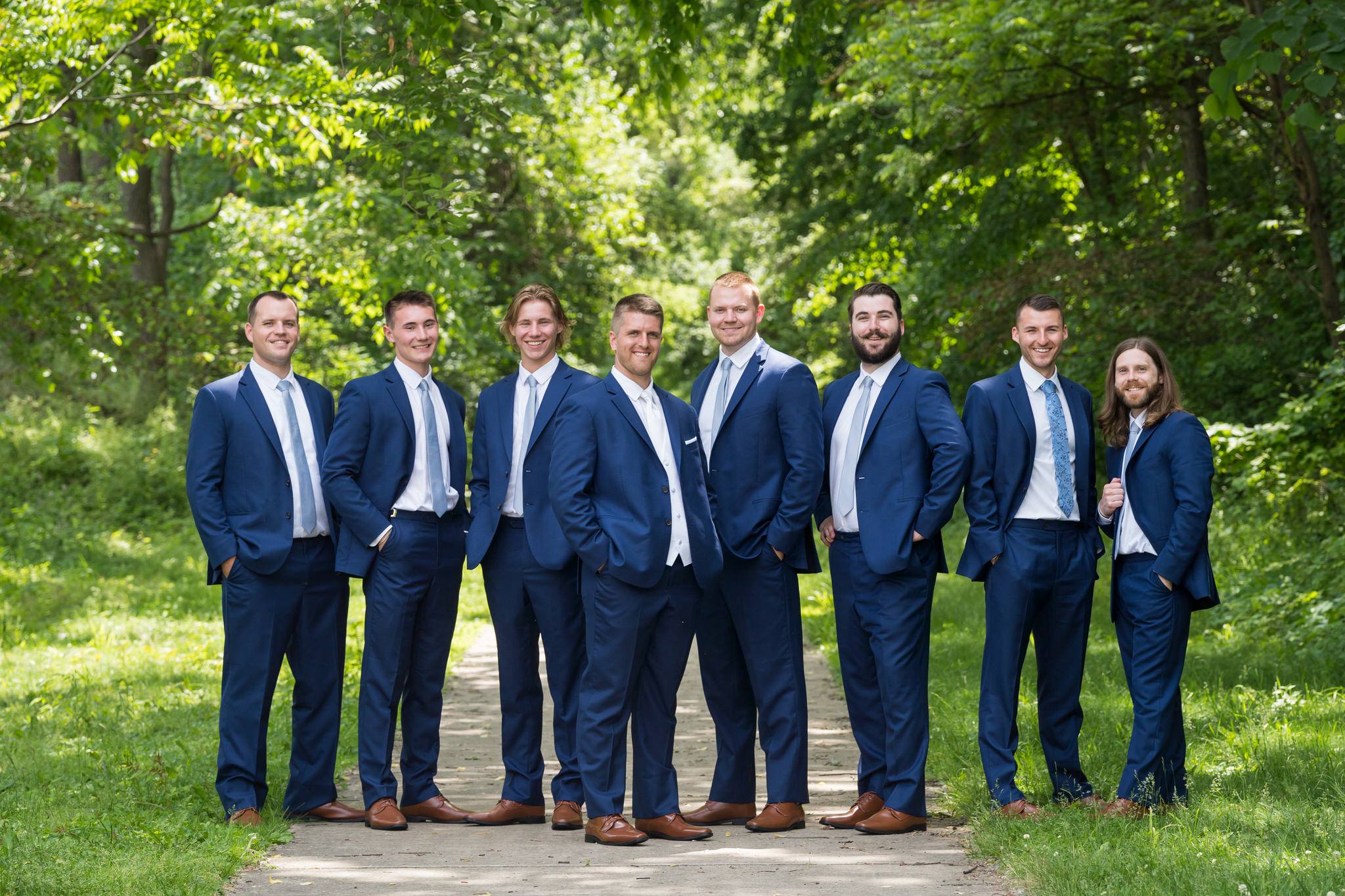 groomsmen stand with hands in their pockets at a wedding at Van Hoosen Museum