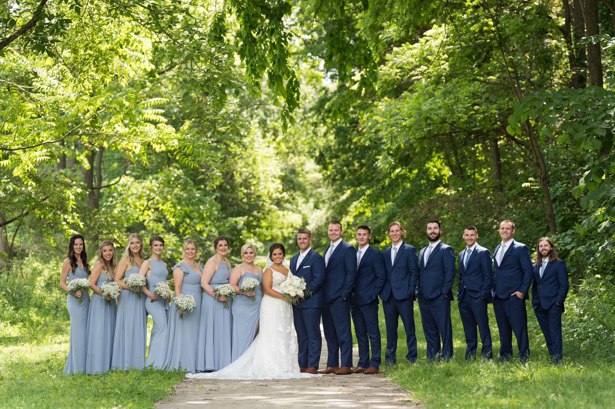 a bridal party stand in a path surrounded by greenery at Van Hoosen Museum
