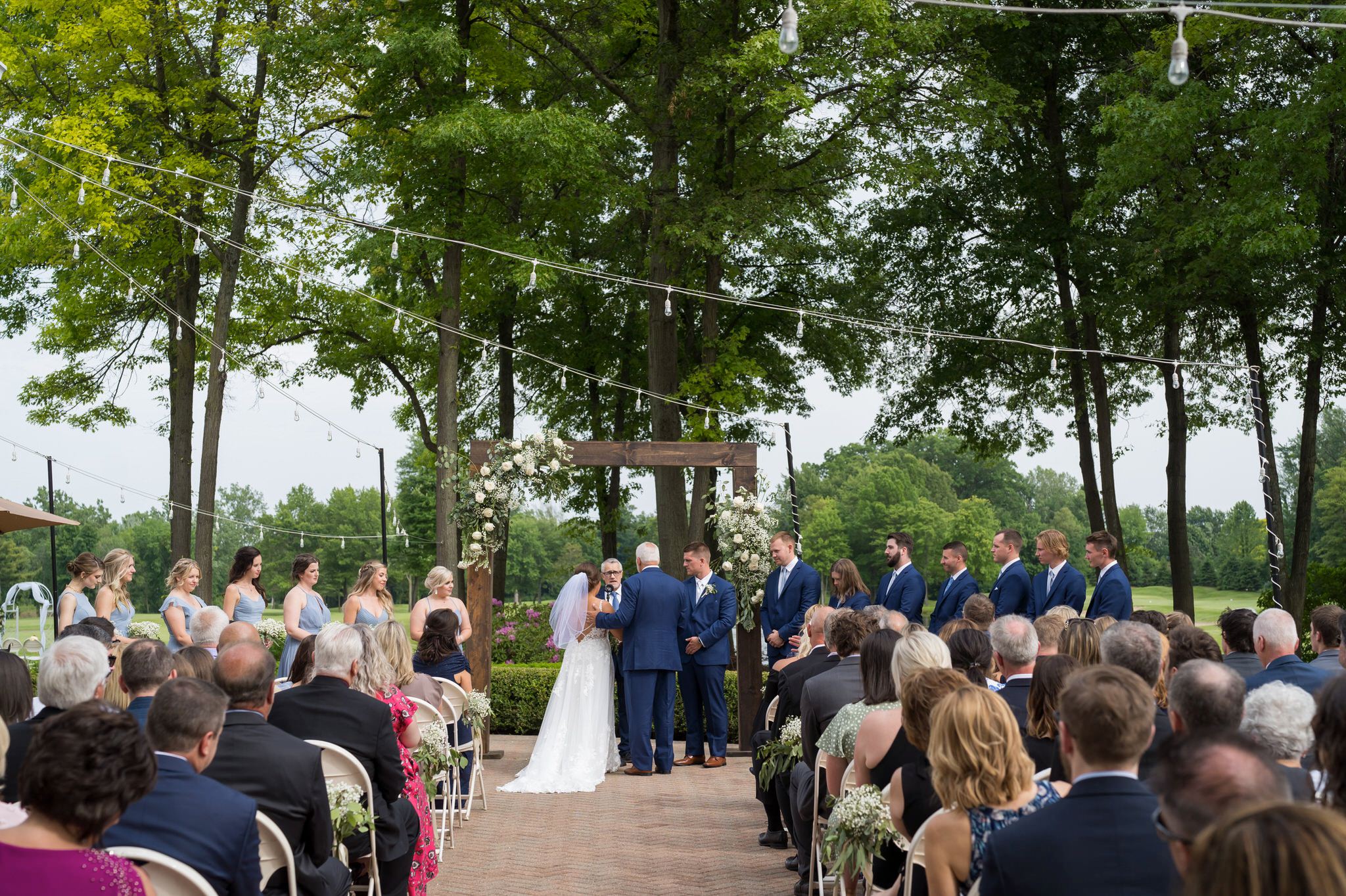 a dad gives away his daughter at wedding at Cherry Creek Golf Course while seated guests look on 