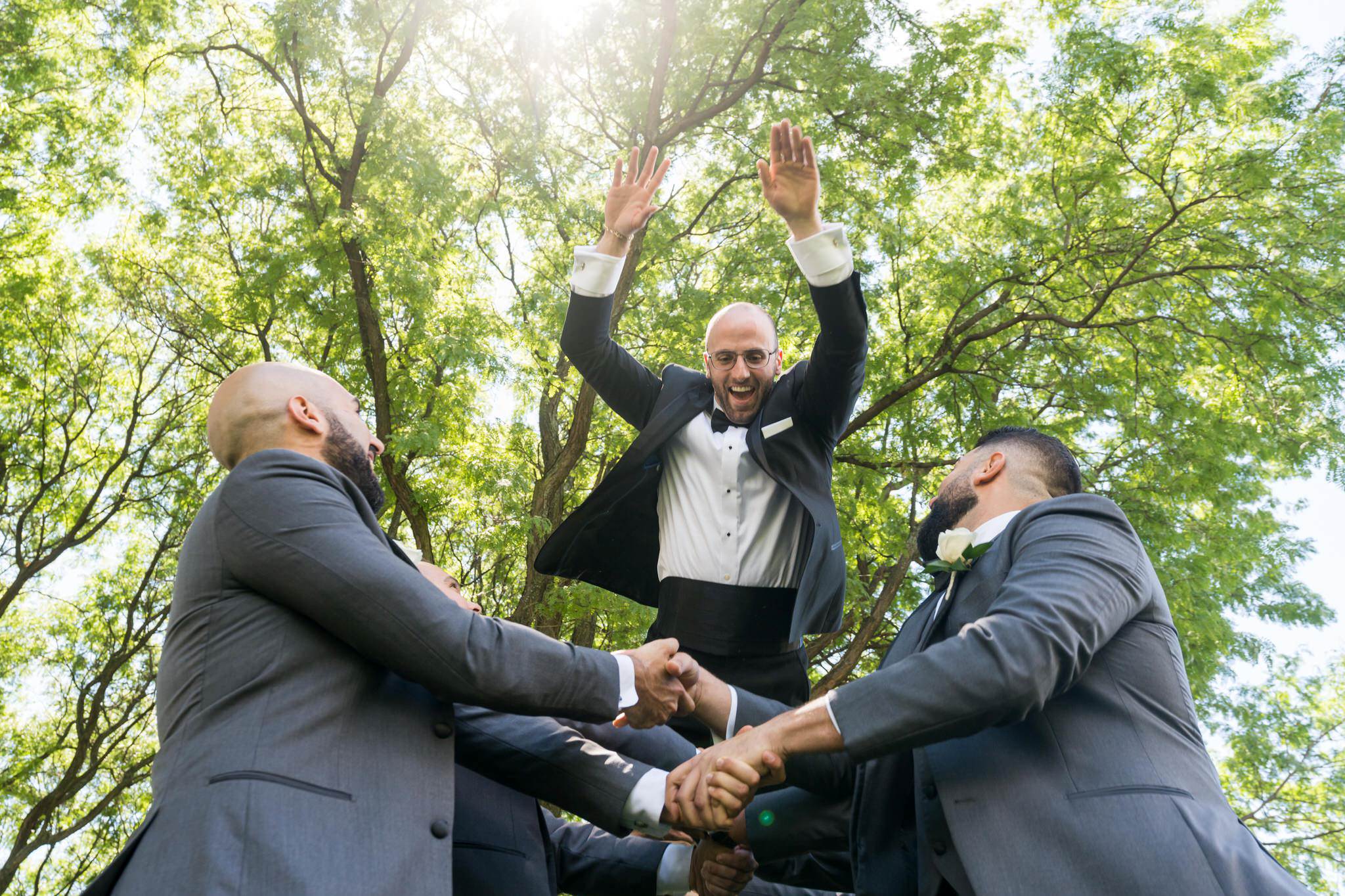 groom is thrown in the air by groomsmen at DIA