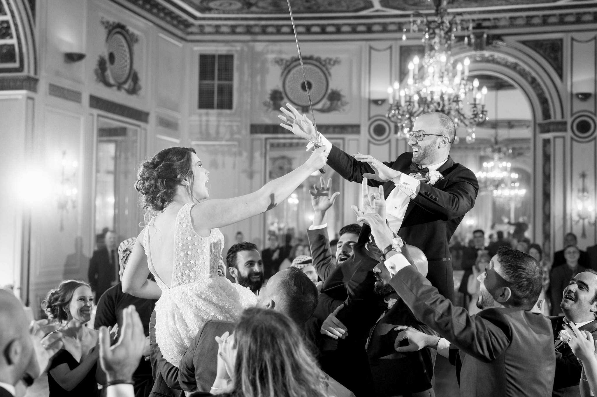 bride and groom sit on the shoulders of guests on the dance floor at their Colony Club wedding