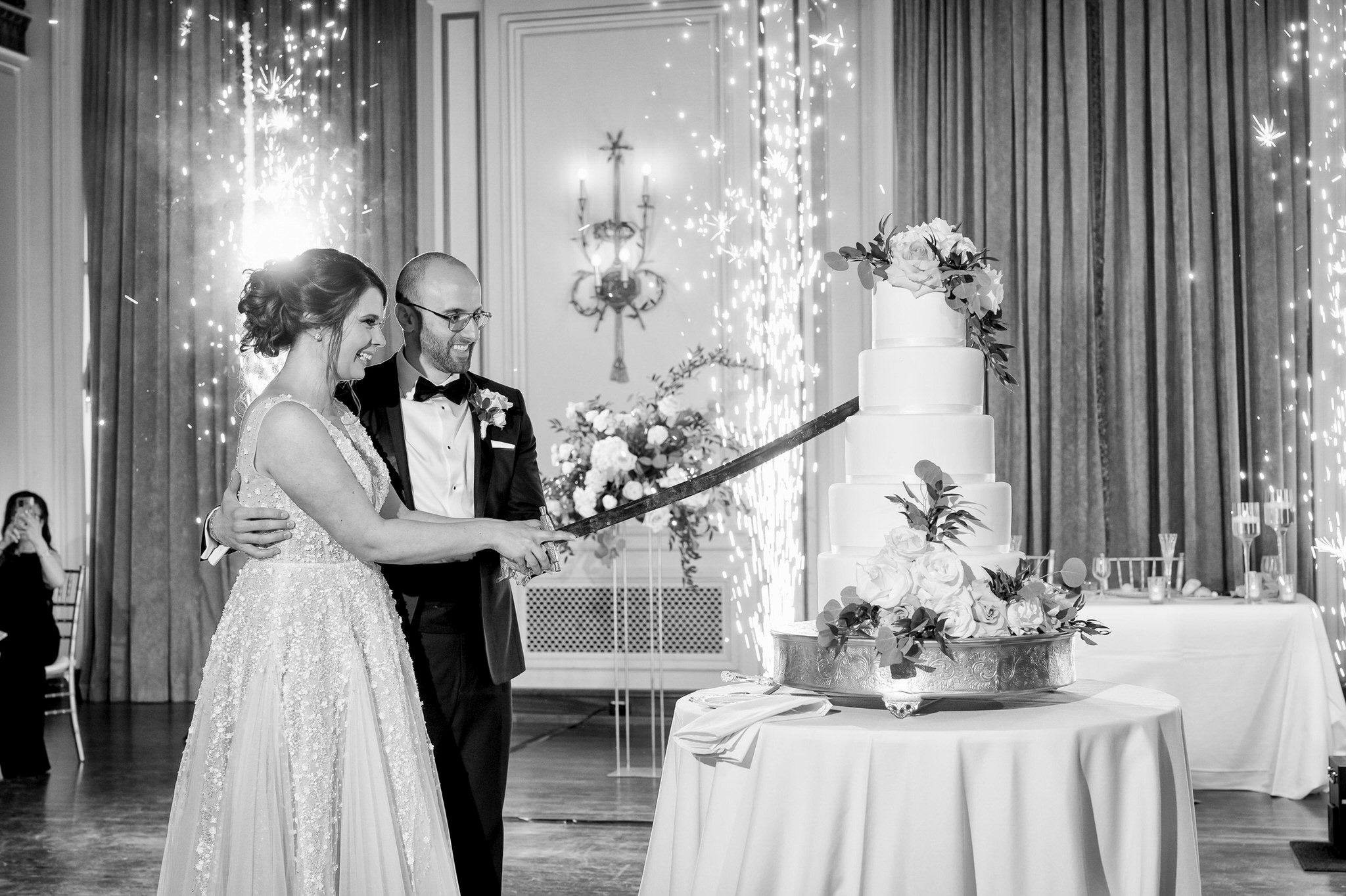 bride and groom cut a wedding cake with a sword at a Colony Club wedding 