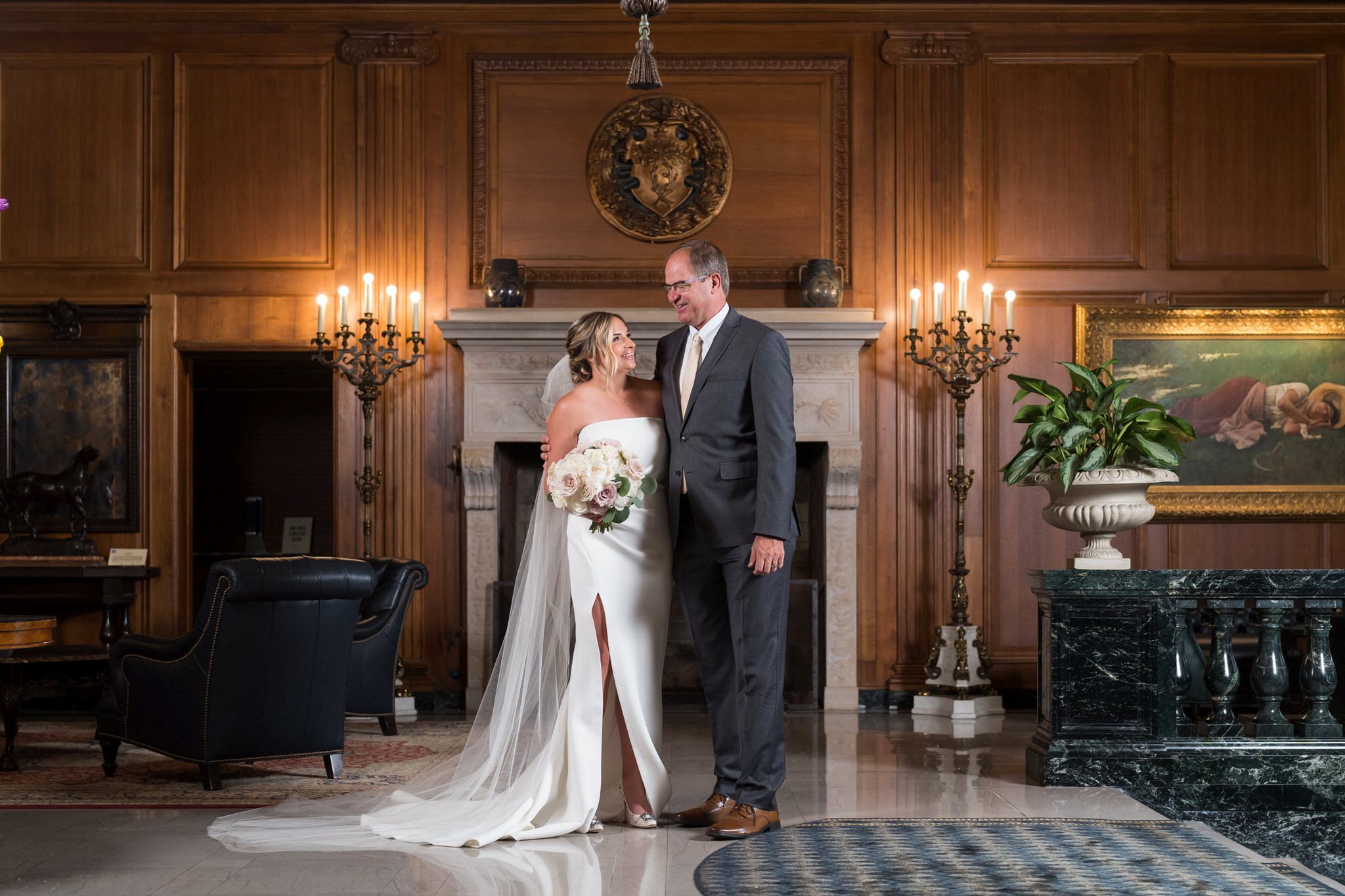 bride and her father hug in front of the fireplace at the Detroit Athletic Club