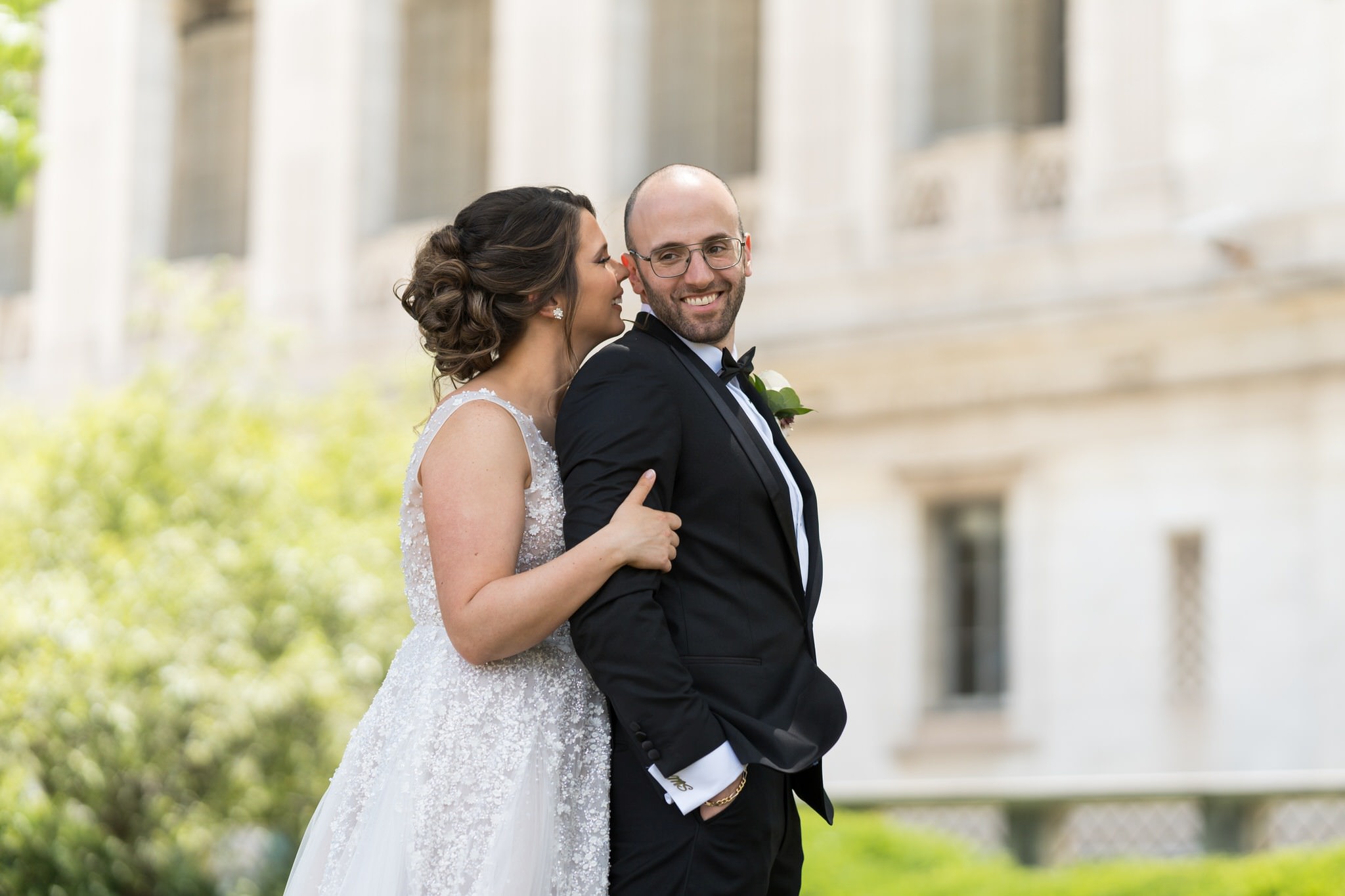 bride hugs groom from behind at Detroit Public Library 