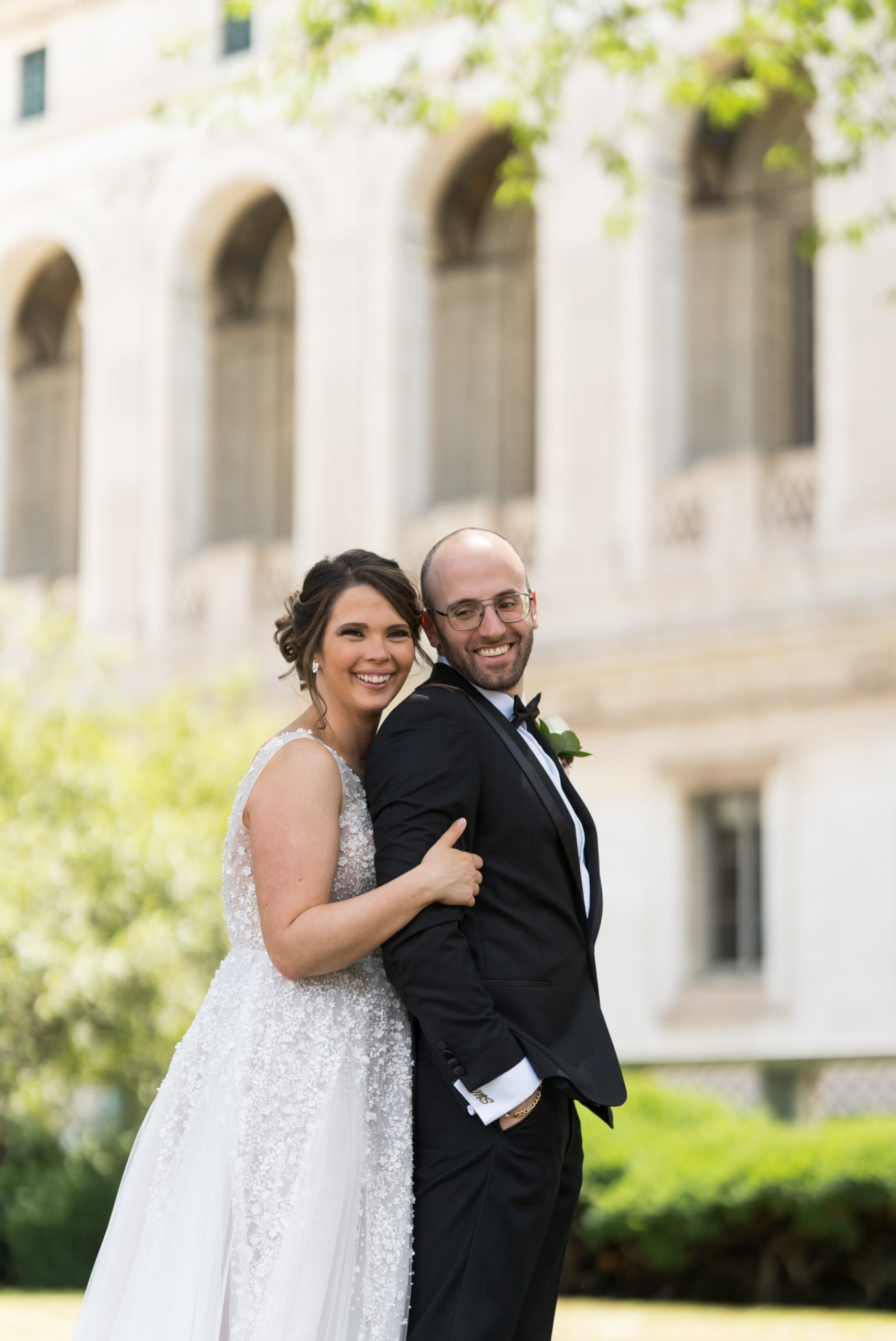 bride hugs groom from behind at Detroit Public Library 