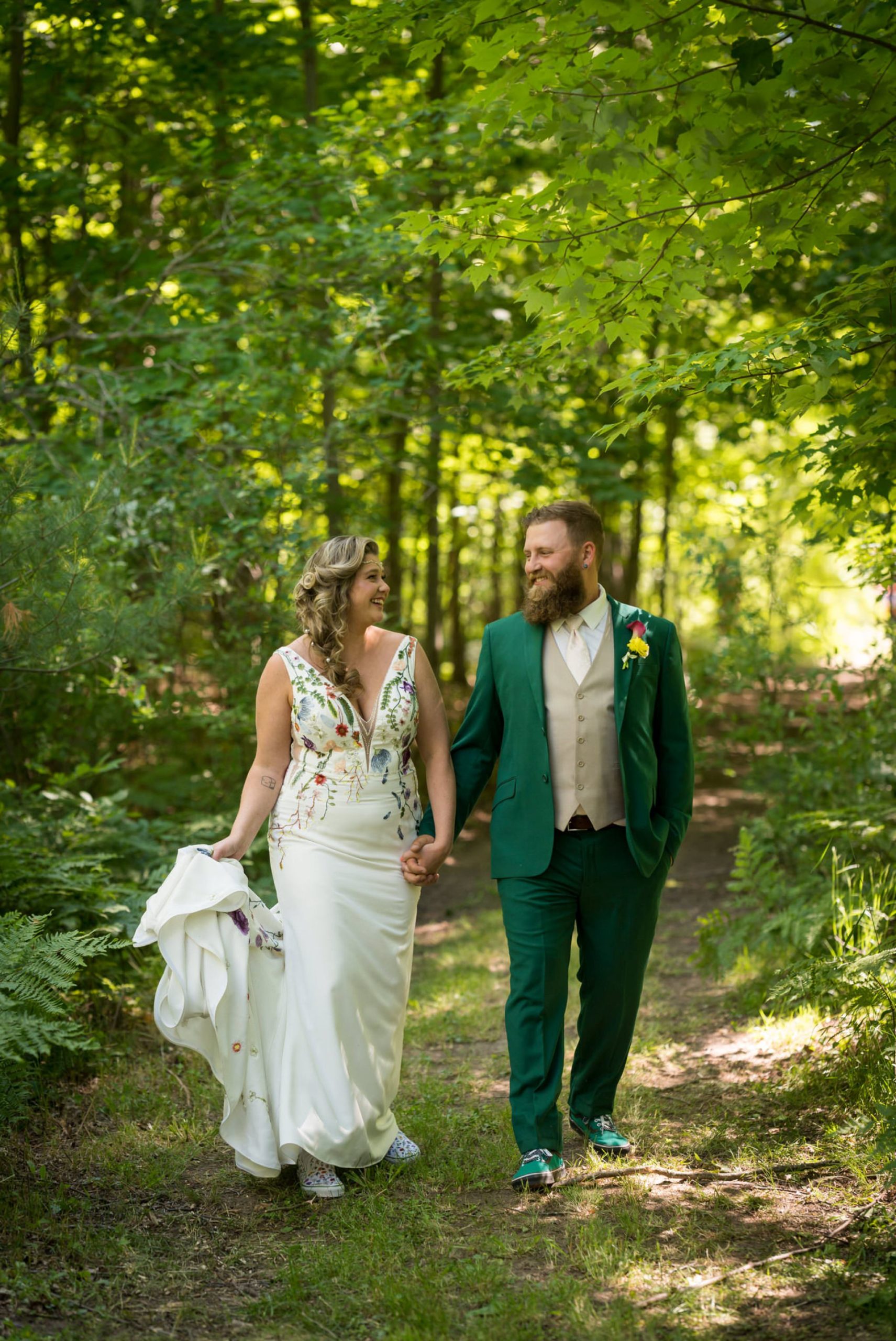 bride and groom walk on a path in the woods on their wedding day