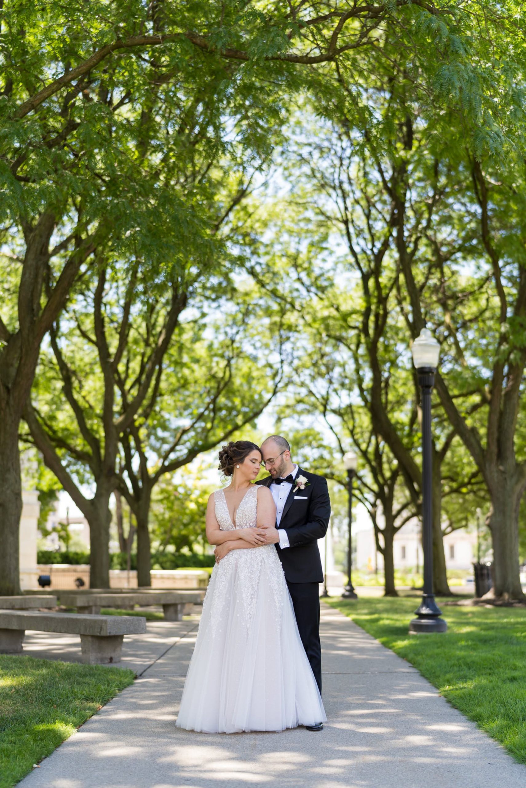 groom hugs bride from behind on a pathway at the Detroit Institute of Arts