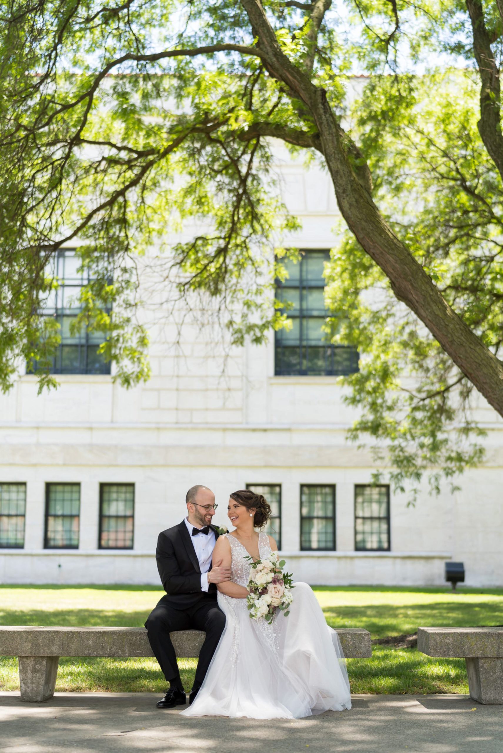 bride and groom sit on a bench outside of Detroit Institute of Arts