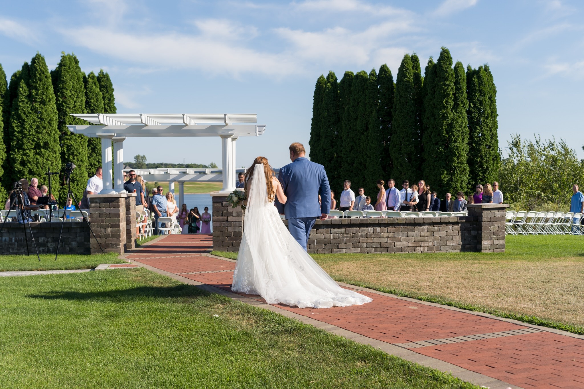 A bride and her father walk towards the ceremony are of a Greystone Golf Club wedding.  