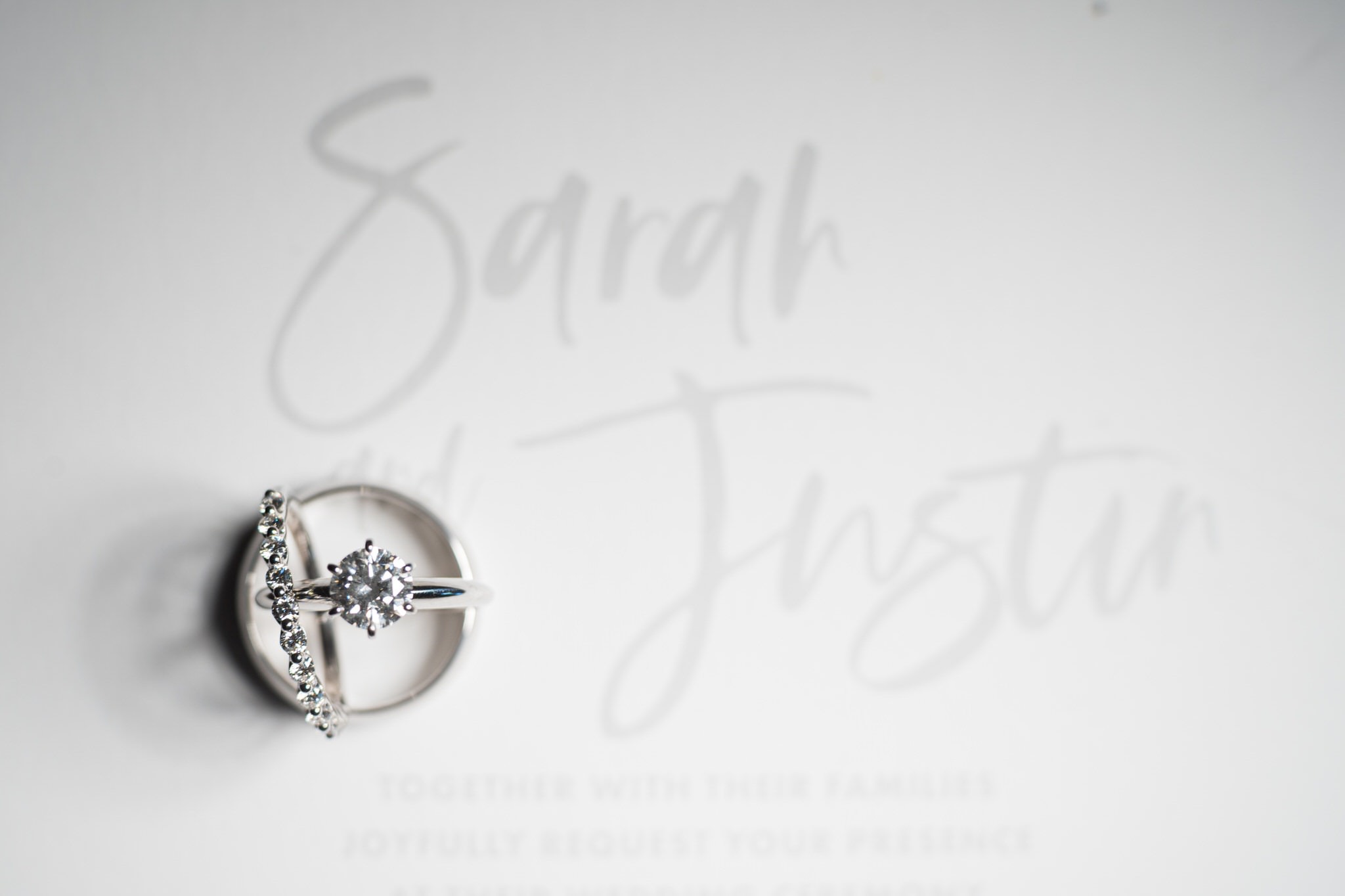 wedding rings balancing on an invite reading Sarah and Justin