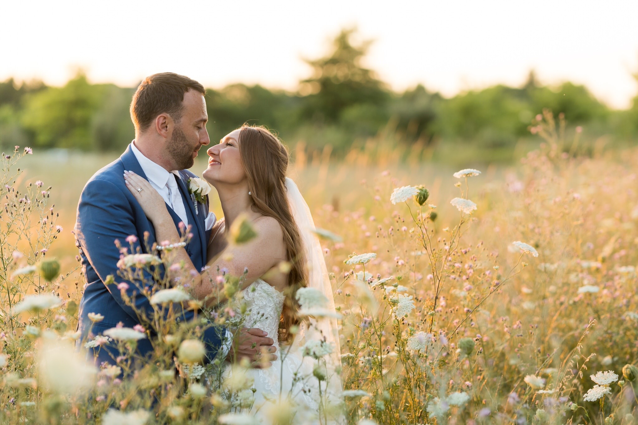 A bride and groom in a field of wildflowers and tall grass in Washington, MI during golden hour. 