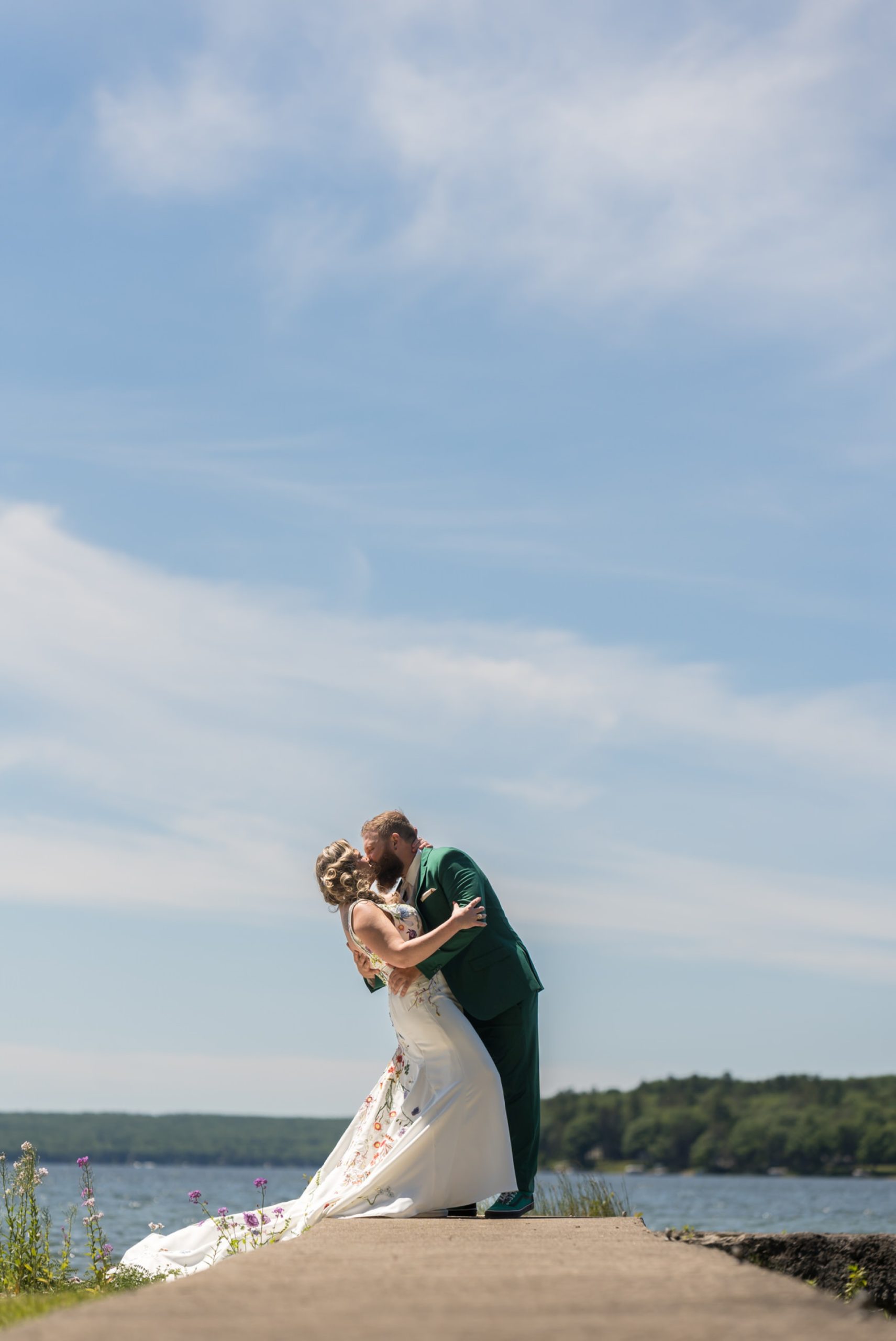 groom dips and kisses a bride at Hubbard Lake, MI