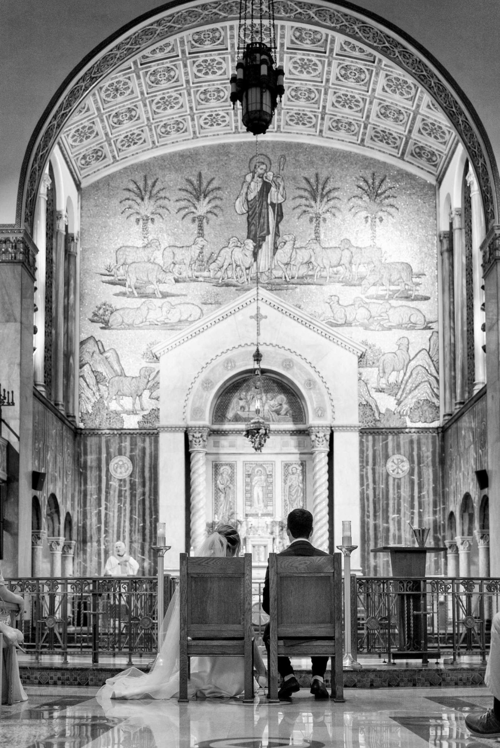 bride and groom sit in chairs near the altar at St. Aloysius Church in Detroit 