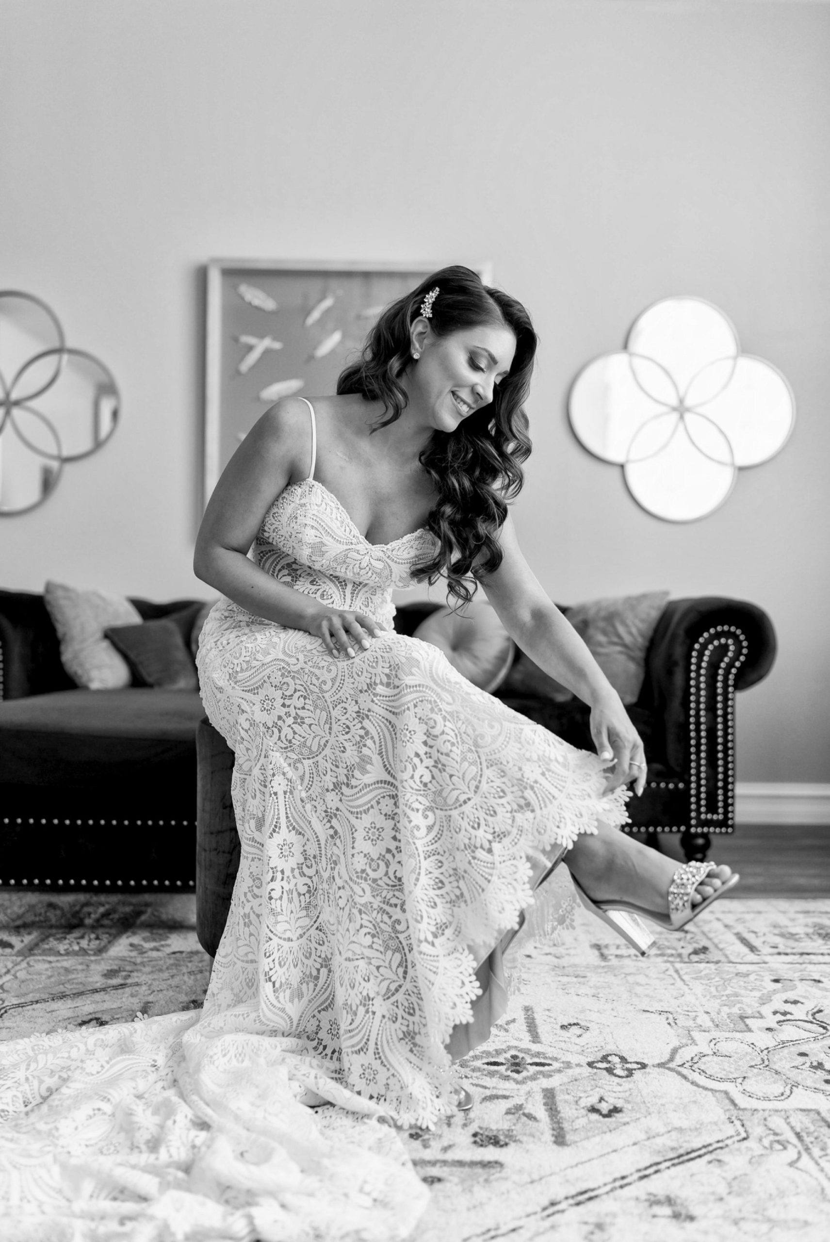 a seated bride fixes her shoes and dress