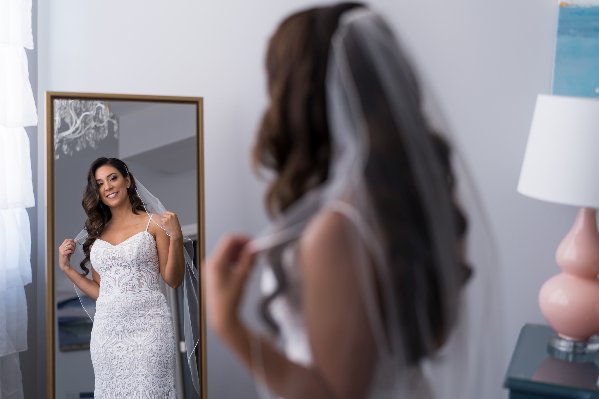 a bride poses in a mirror prior to her Holly Vault wedding 