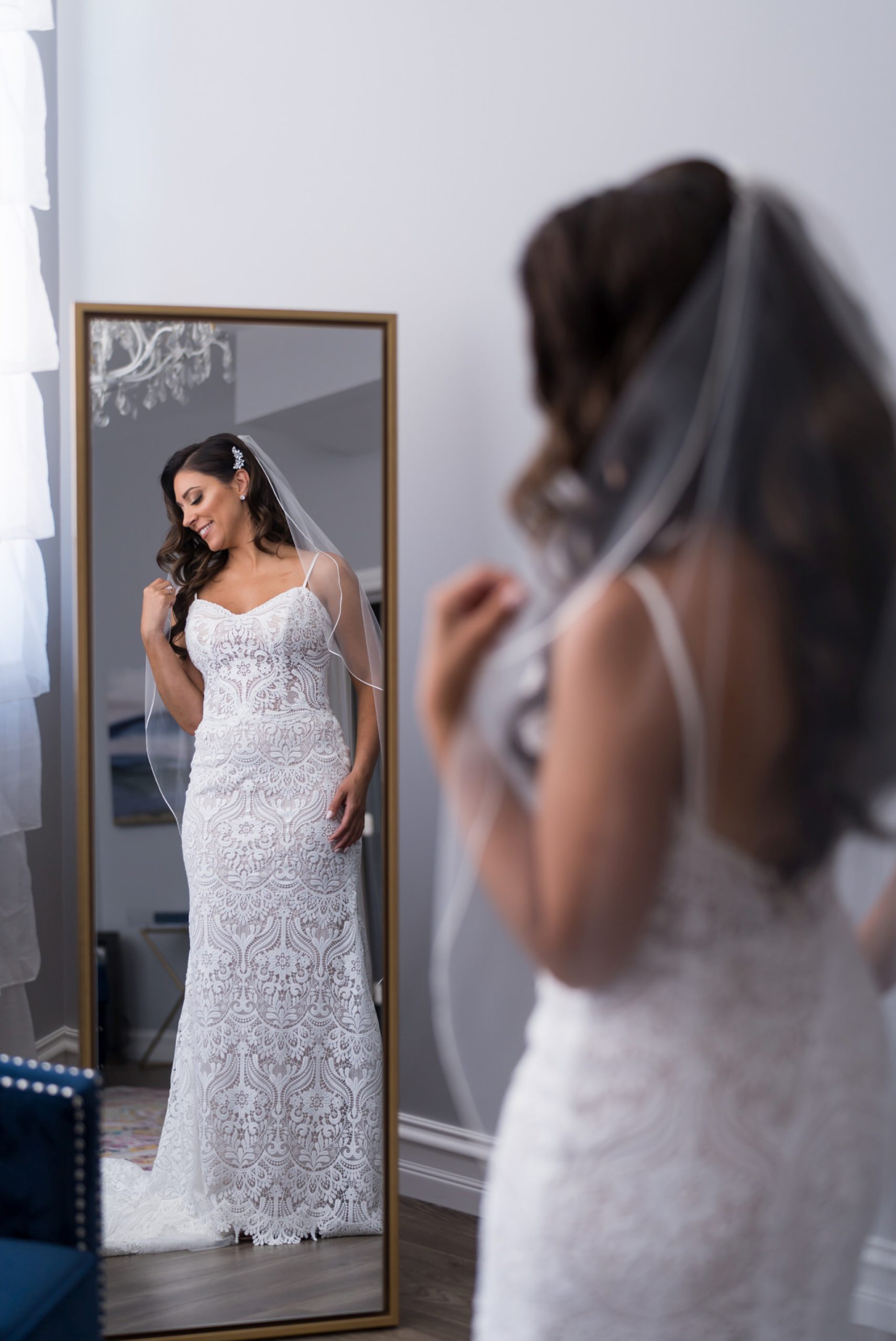 a bride poses in a mirror prior to her Holly Vault wedding 
