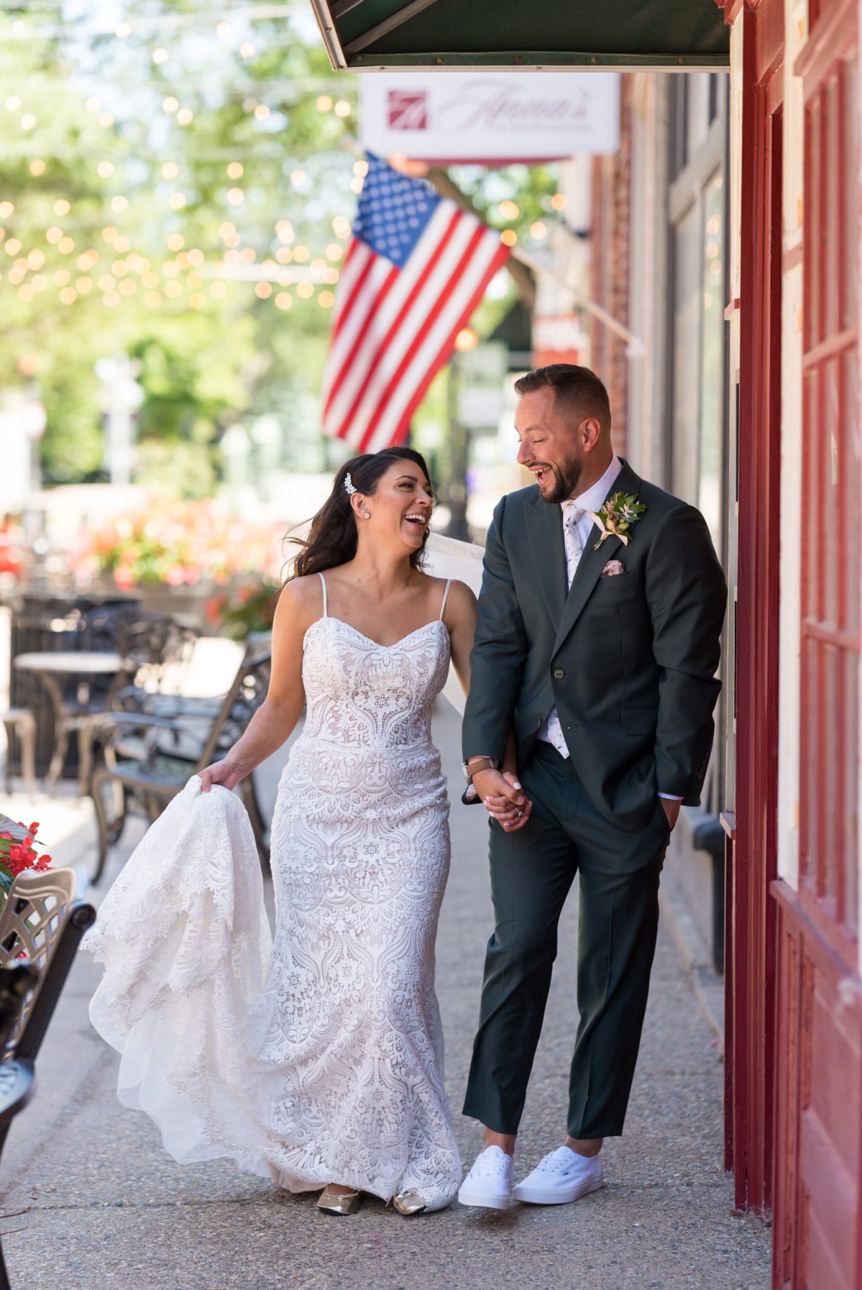 bride and groom walk and laugh with an American flag in the background at their Holly vault wedding 