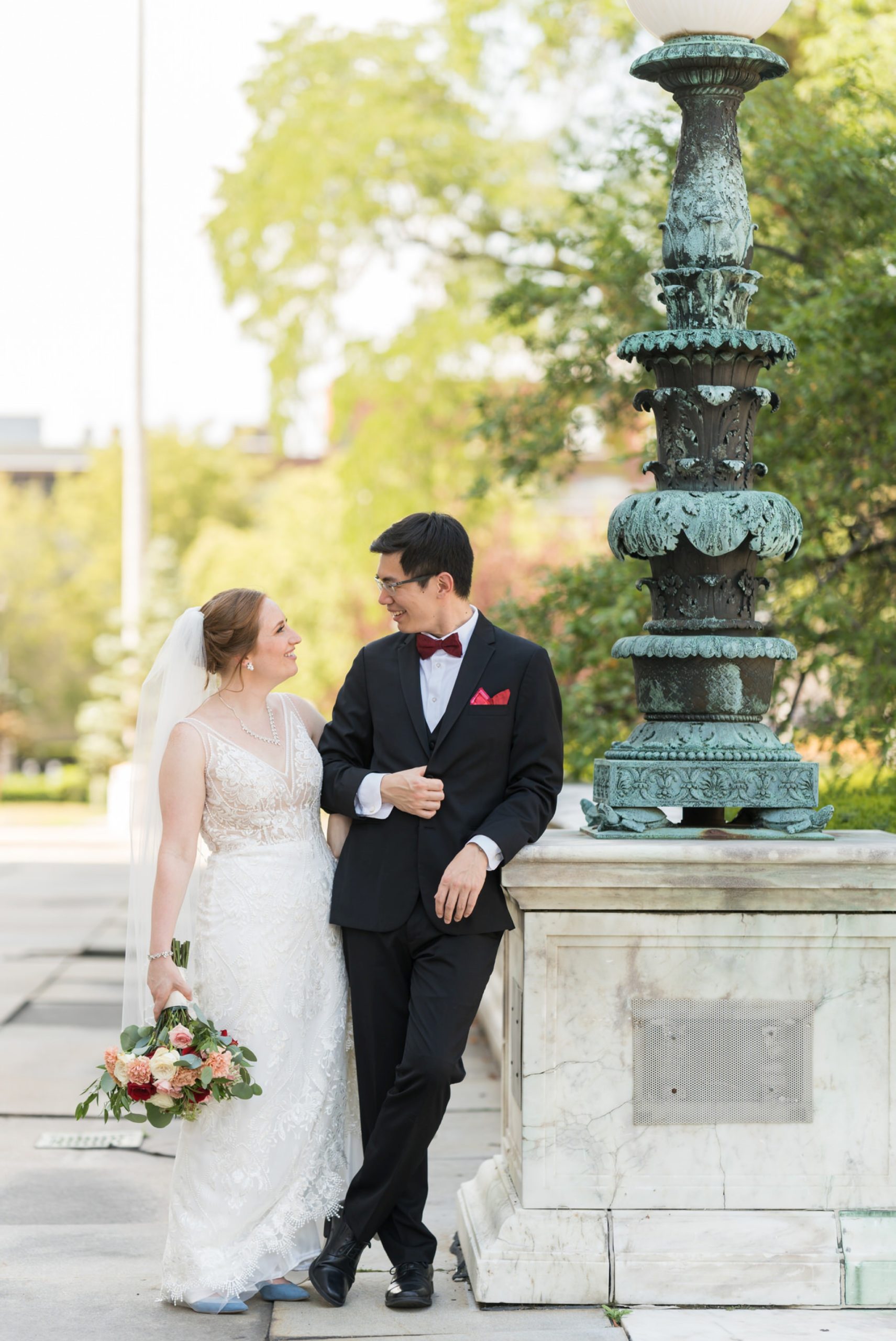 A bride and groom pose, leaning on a marble block on their wedding day, at the Detroit Public Library by Brian Weitzel Photography