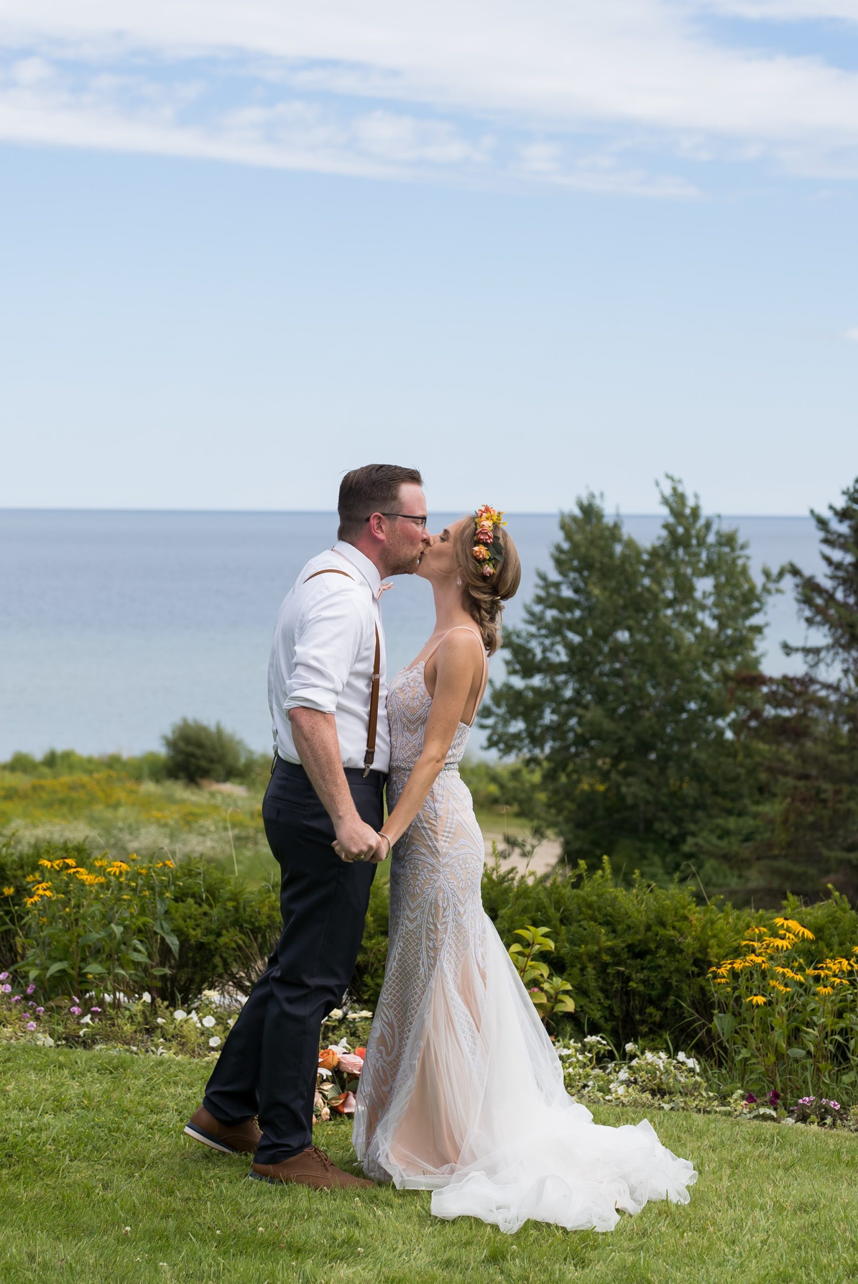 A bride and groom hold hands and kiss each other on the bluff of Mission Pointe Resort on Mackinac Island.
