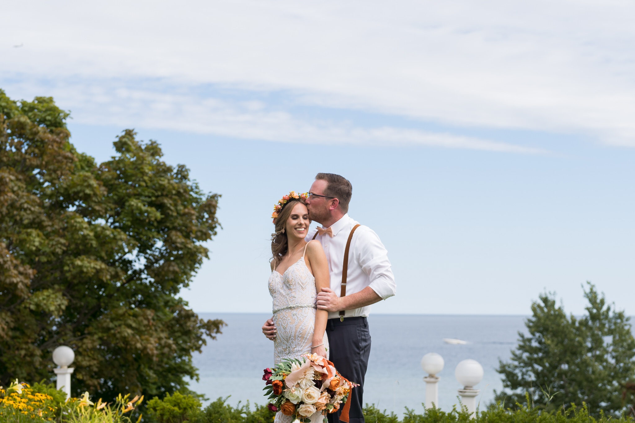 A bride is kissed from her husband on a bluff at their Mission Point Resort wedding.  
