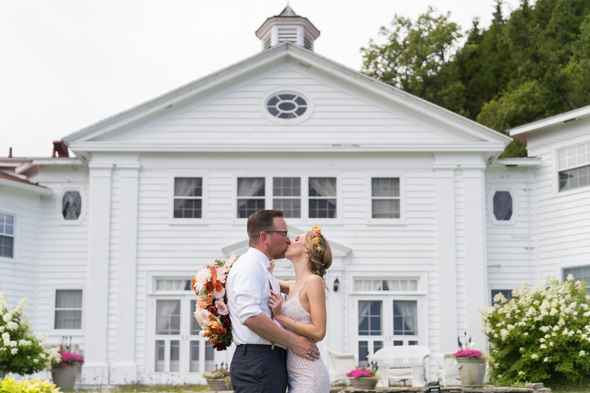 A bride and groom kiss in front of the Mission Pointe Resort on Mackinac Island.